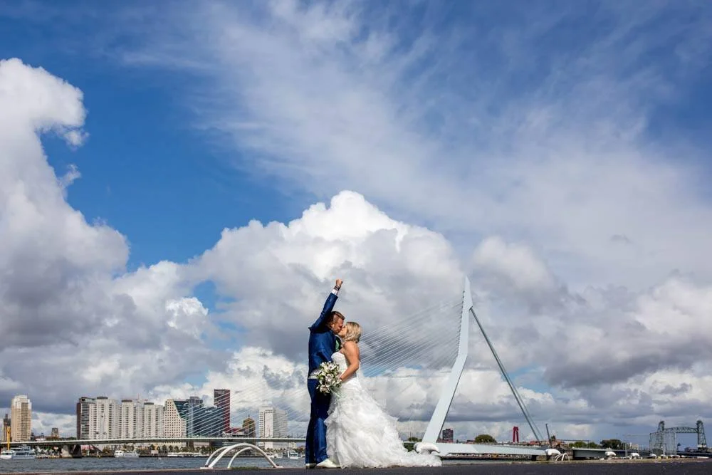 Trouwfoto in Rotterdam bij de Erasmusbrug met een bruidspaar tijdens een ontspannen fotoshoot