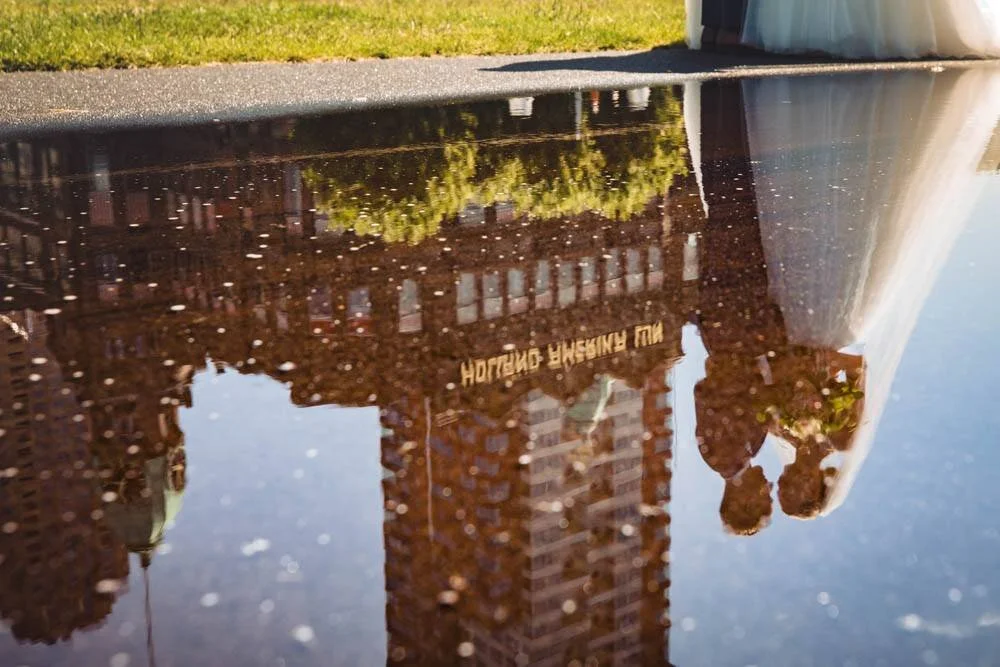 Spelen met de weerspiegeling in de regenplas bij een fotoshoot met een bruidspaar bij Hotel New York in Rotterdam