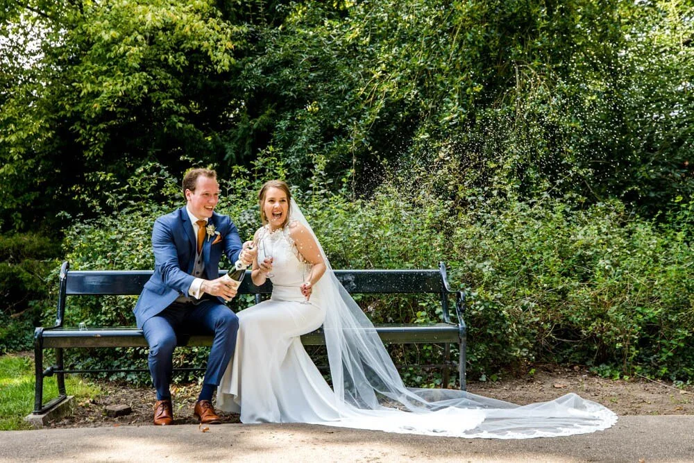 Tijdens een ontspannen fotoshoot popt het bruidspaar de champagne in het park in Utrecht