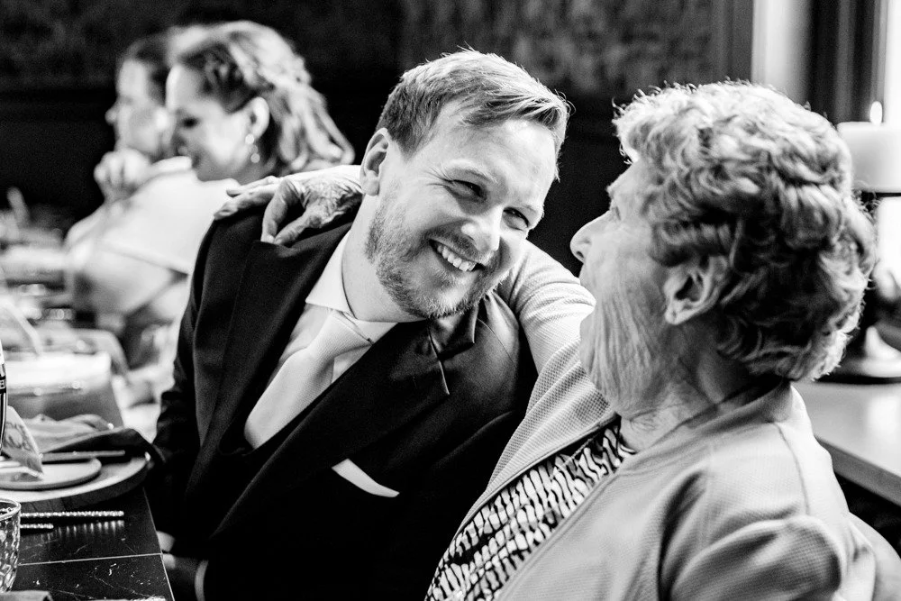 een spontaan moment tussen oma en de bruidegom tijdens het diner is een voorbeeld van documentaire trouwfotografie in Brabant