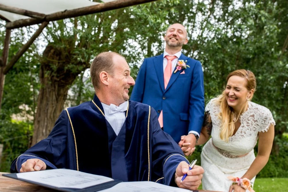 pure trouwfoto vol humor tijdens de ceremonie in utrecht tussen bruidspaar en de trouwambtenaar