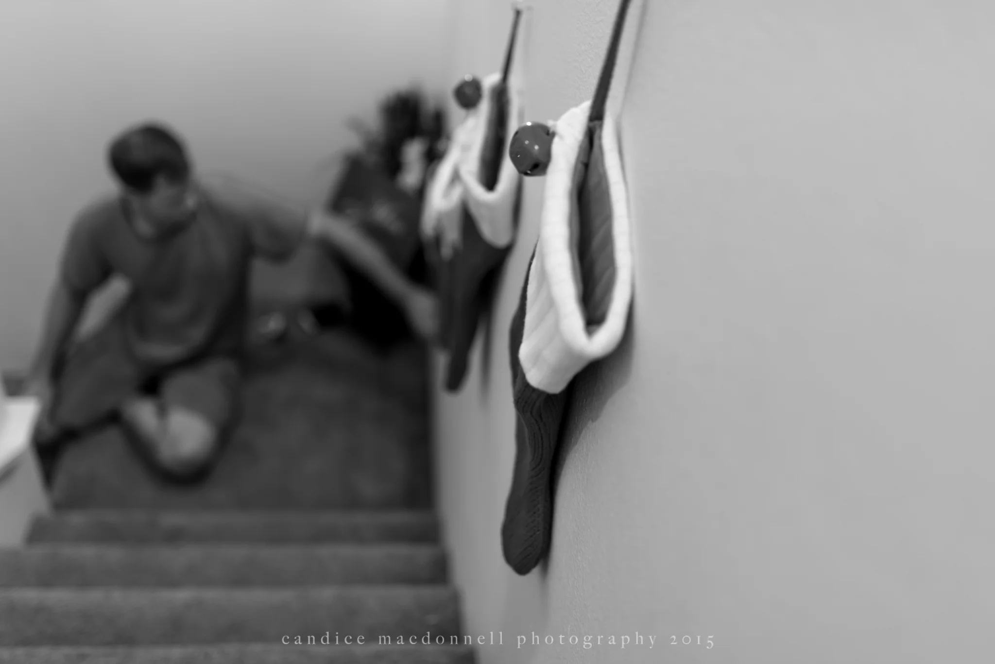 husband hanging christmas stockings on stairwell © candice macdonnell 2015