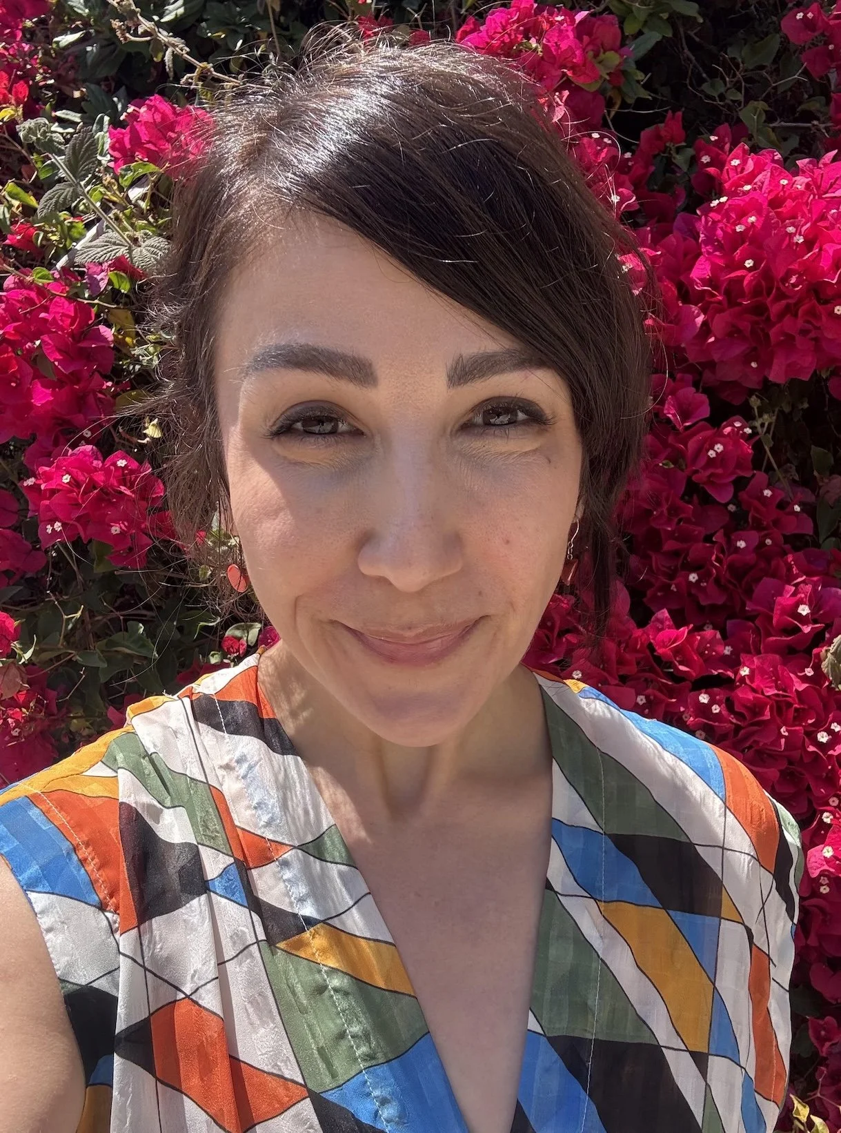 Portrait of Lainna Fader smiling in front of pink bougainvillea.