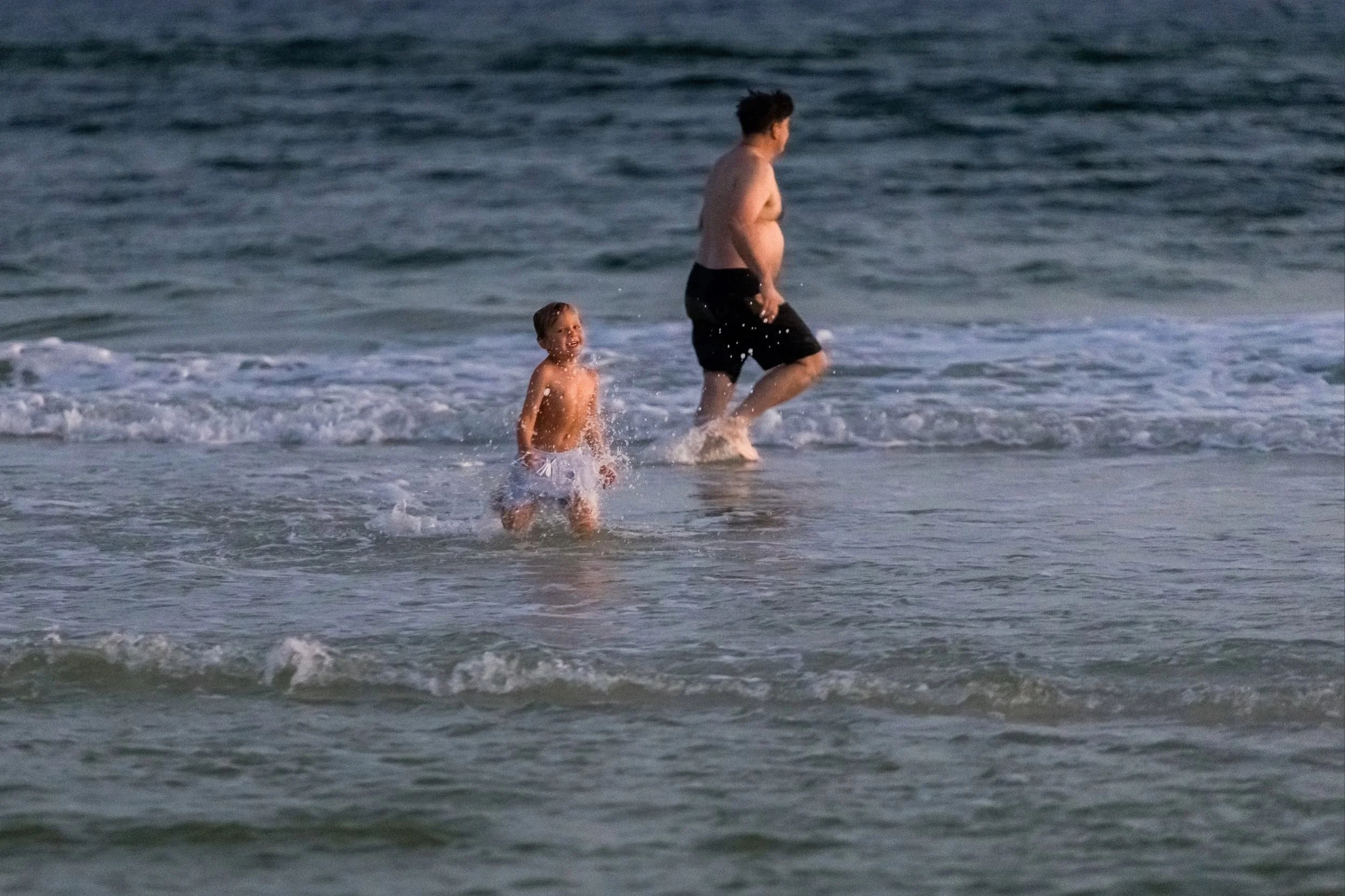 Grandfather and grandson playing in the waves in Watercolor Florida at sunset.