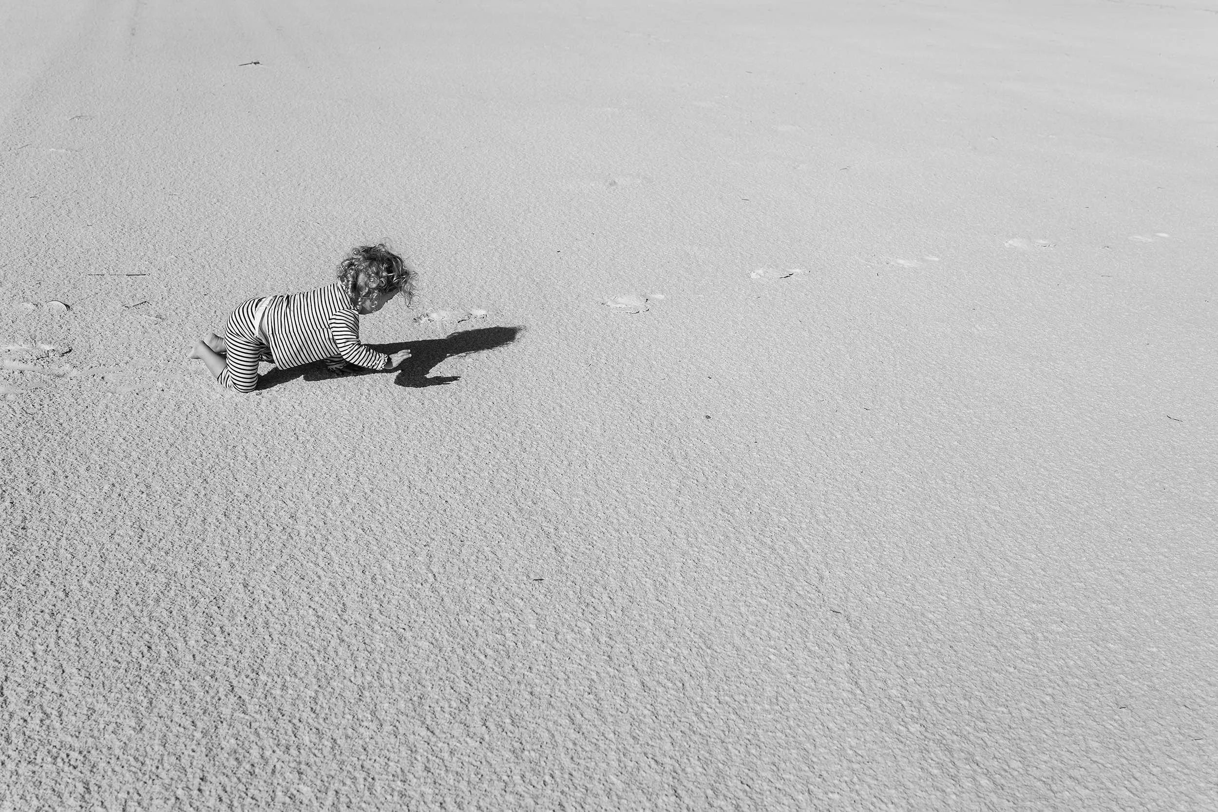 toddler crawling on watersound  beach during natural family photo session.
