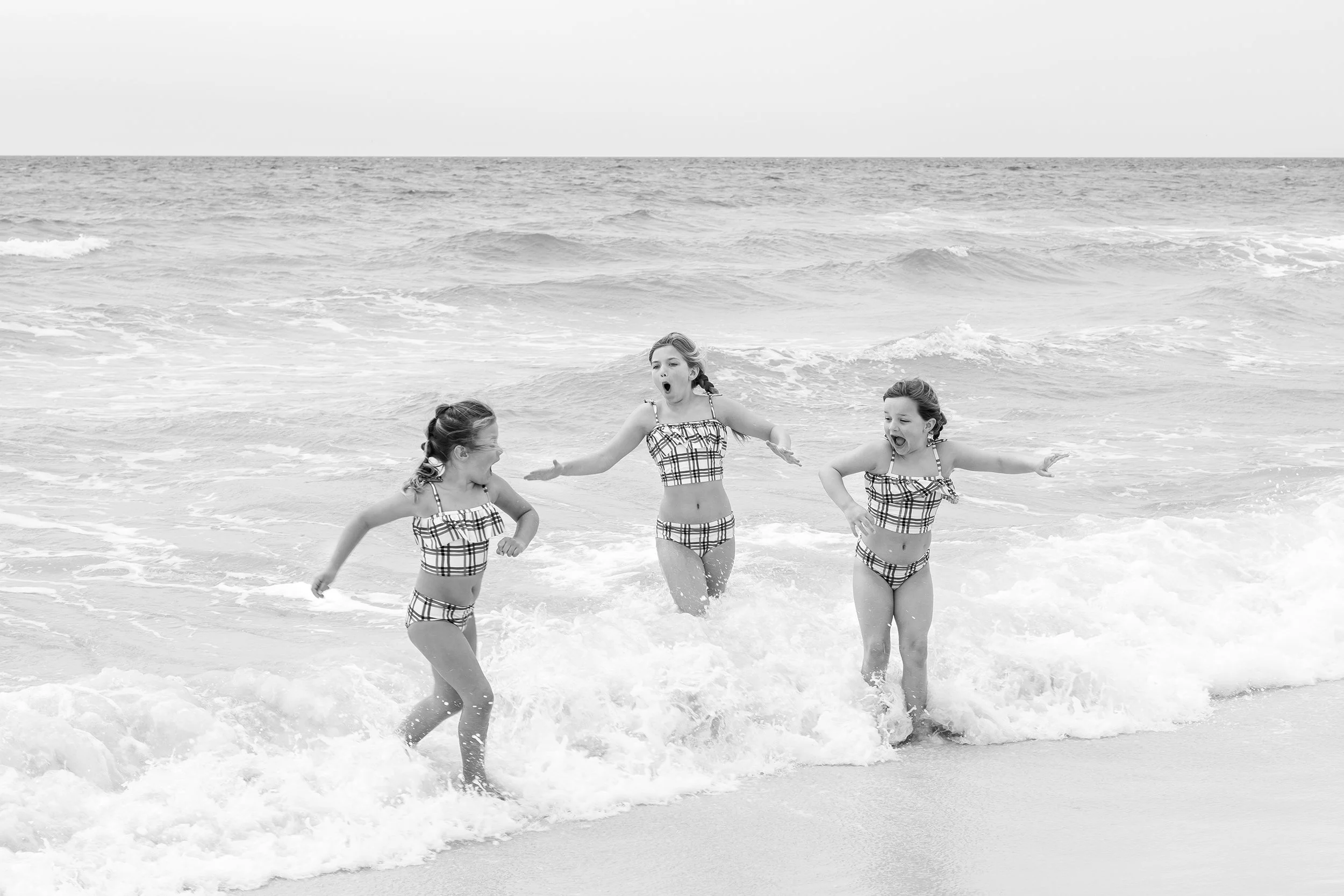 three sisters in matching swimsuits running out of the waves on 30A