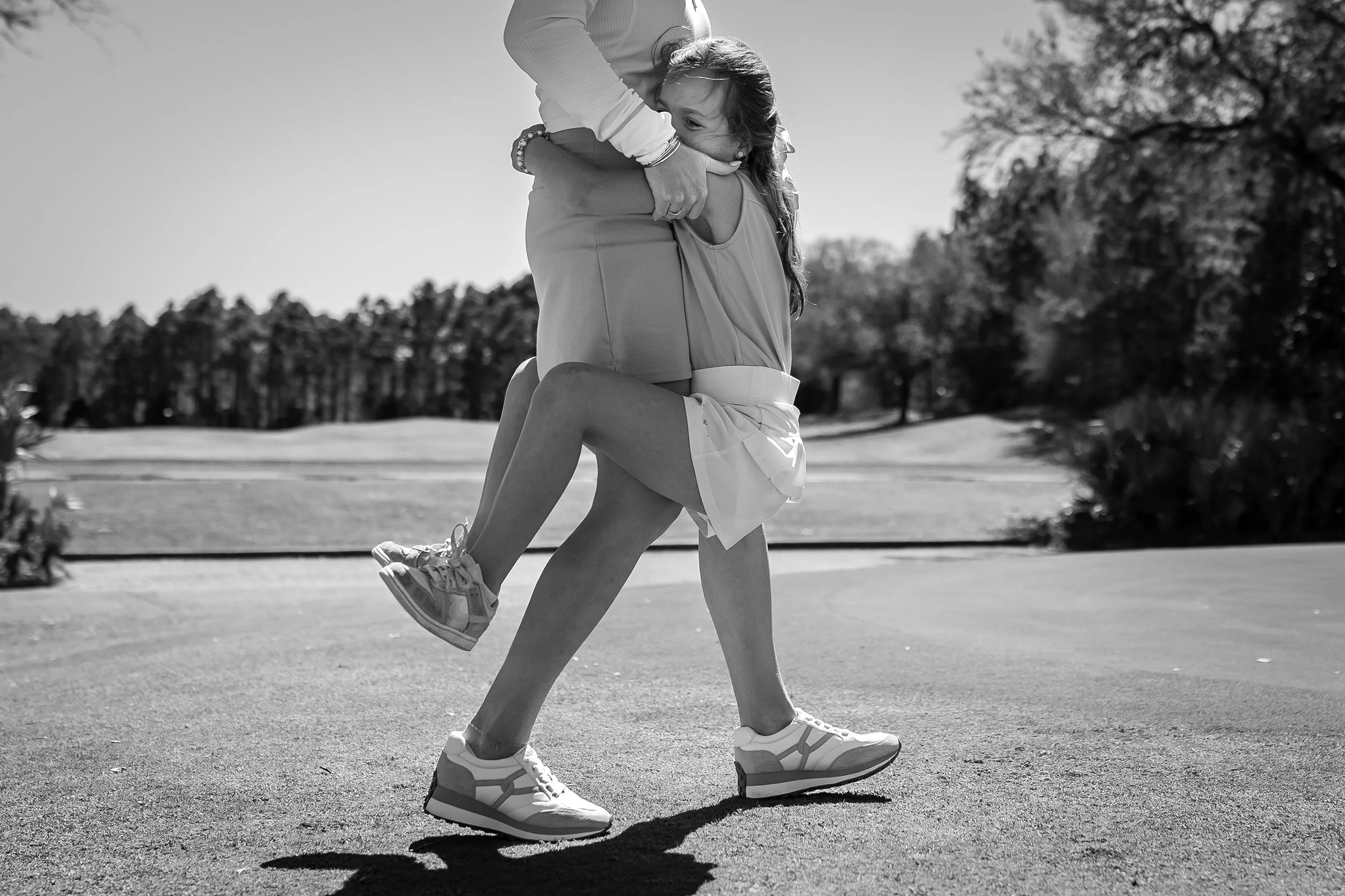 Little girl holding onto her mother's waist with her legs wrapped around her on the Camp Creek golf course