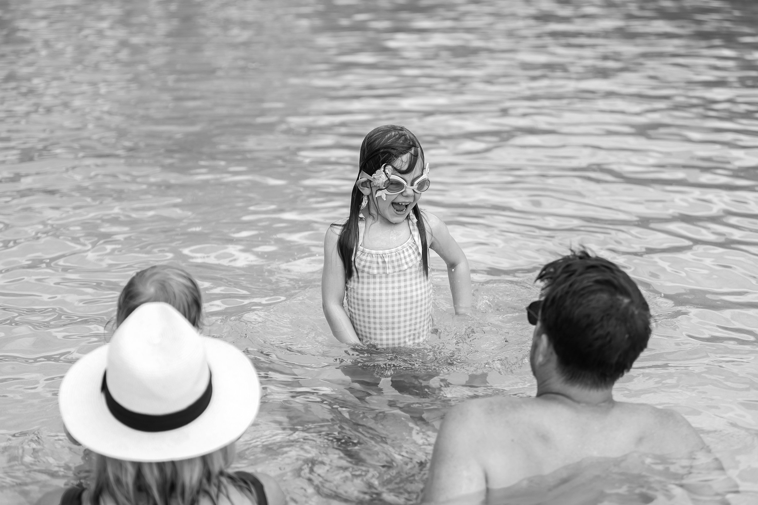Little girl in goggles smiling at her family in the Watercolor pool.