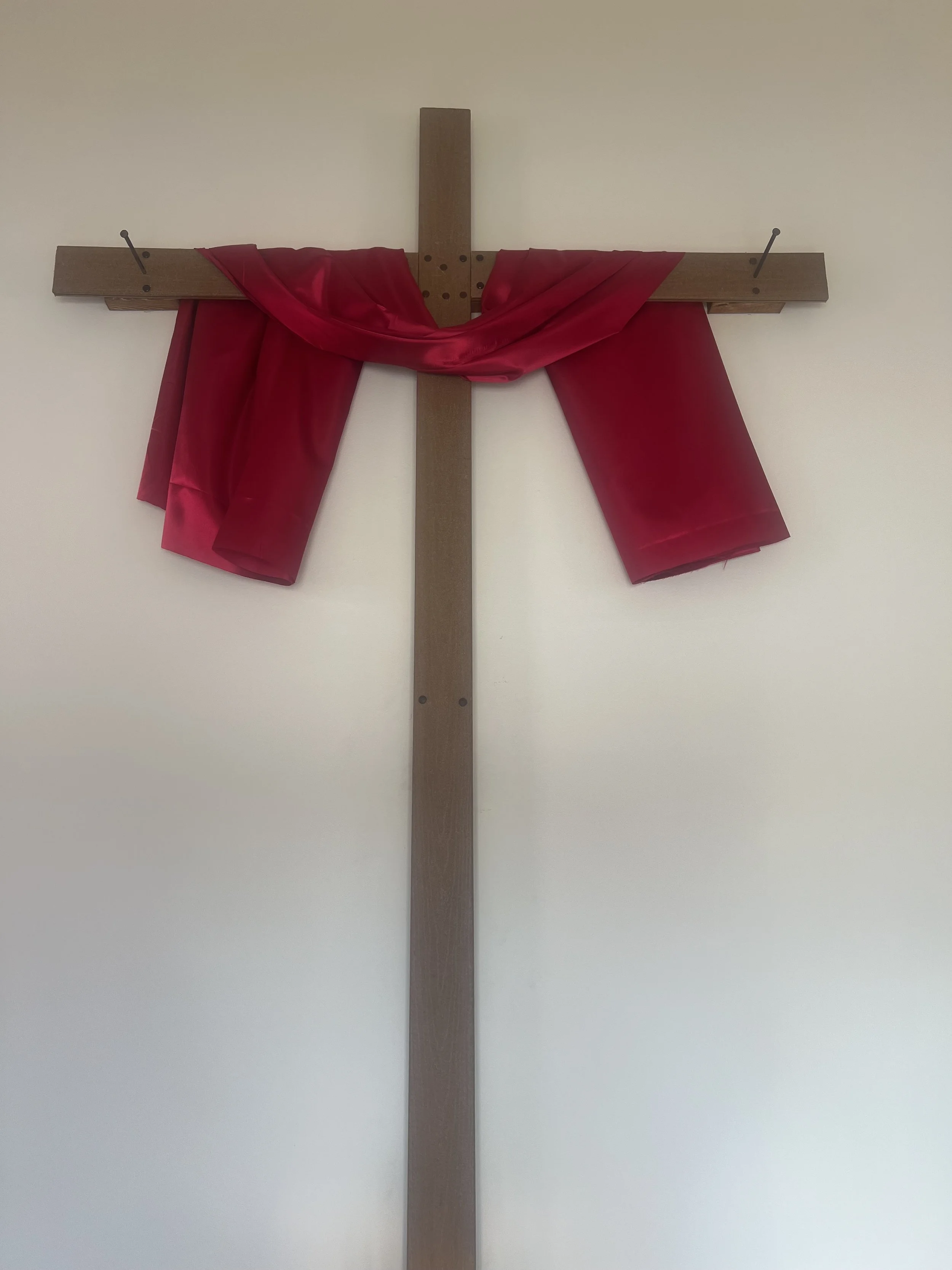 Wooden cross with red cloth draped over the horizontal beam.