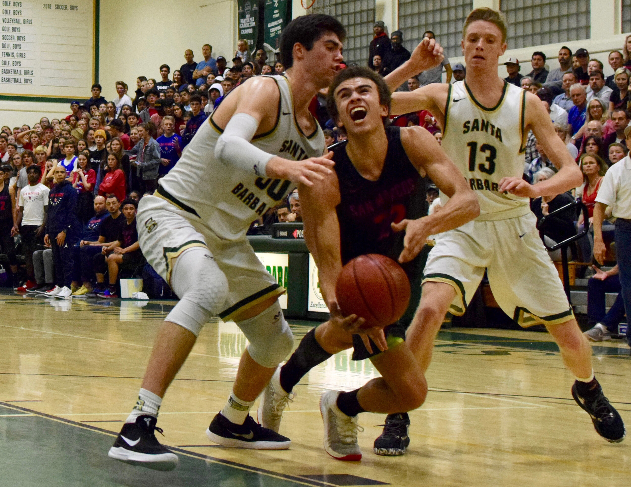  Santa Barbara High School’s Don's Bryce Warrecker #30 (left) and Aiden Douglas #13 take on San Marcos High School’s Royals' Beau Allen (center).    