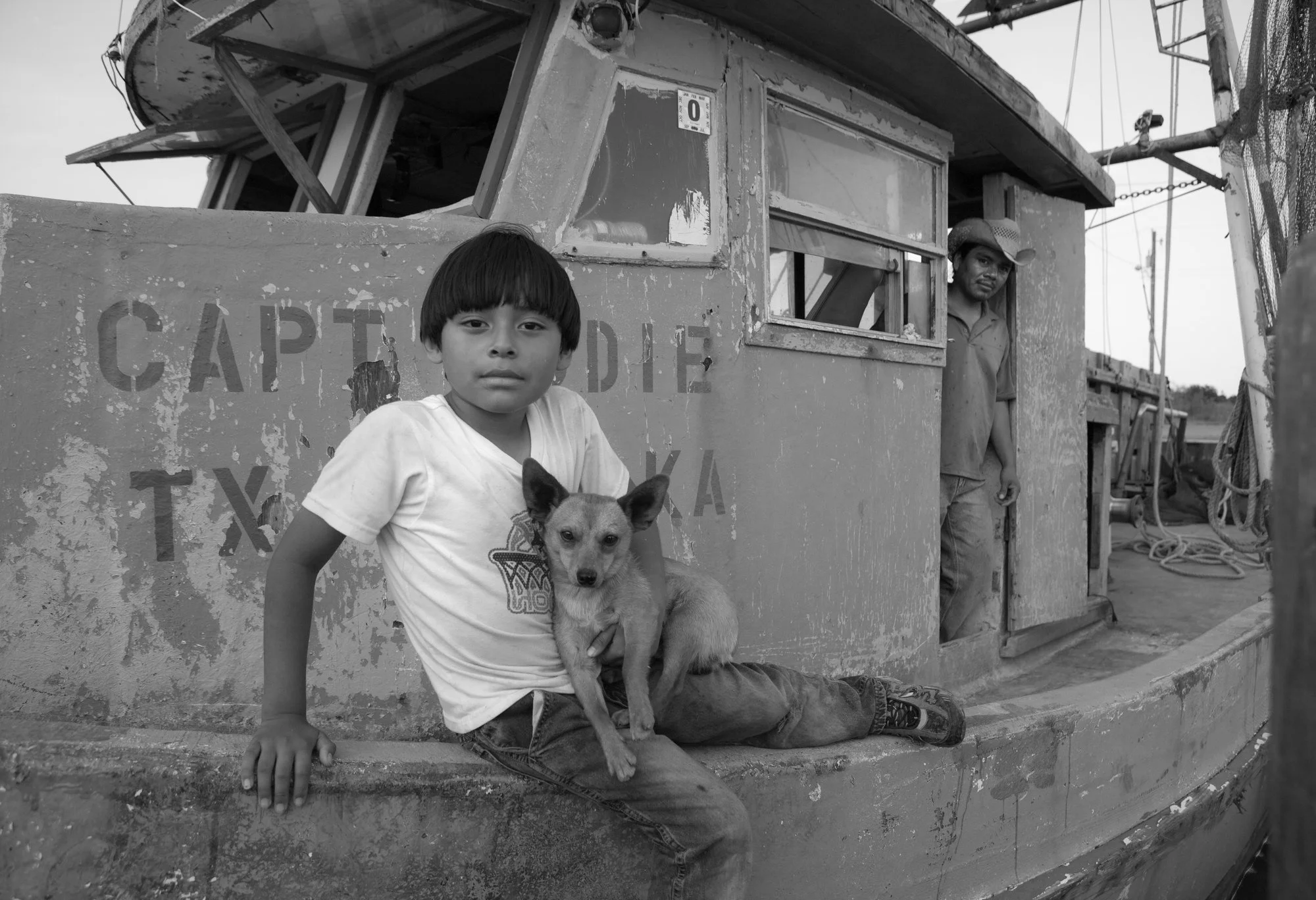 Vietnamese boy and dog on family shrimp boat, Aransas Pass, Texas
