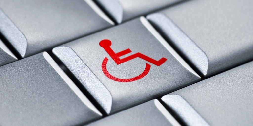Closeup of a grey computer keyboard with a red wheelchair symbol on the center key