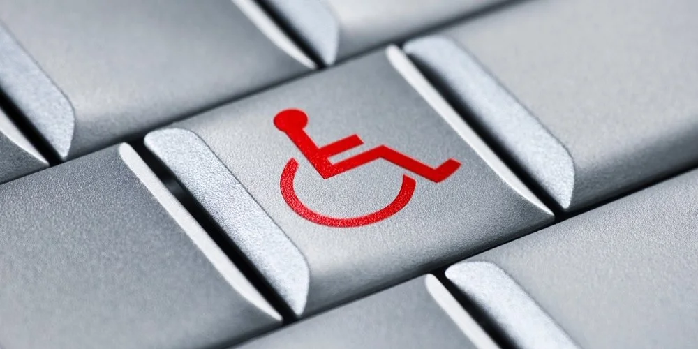 Closeup of a grey computer keyboard with a red wheelchair symbol on the middle key