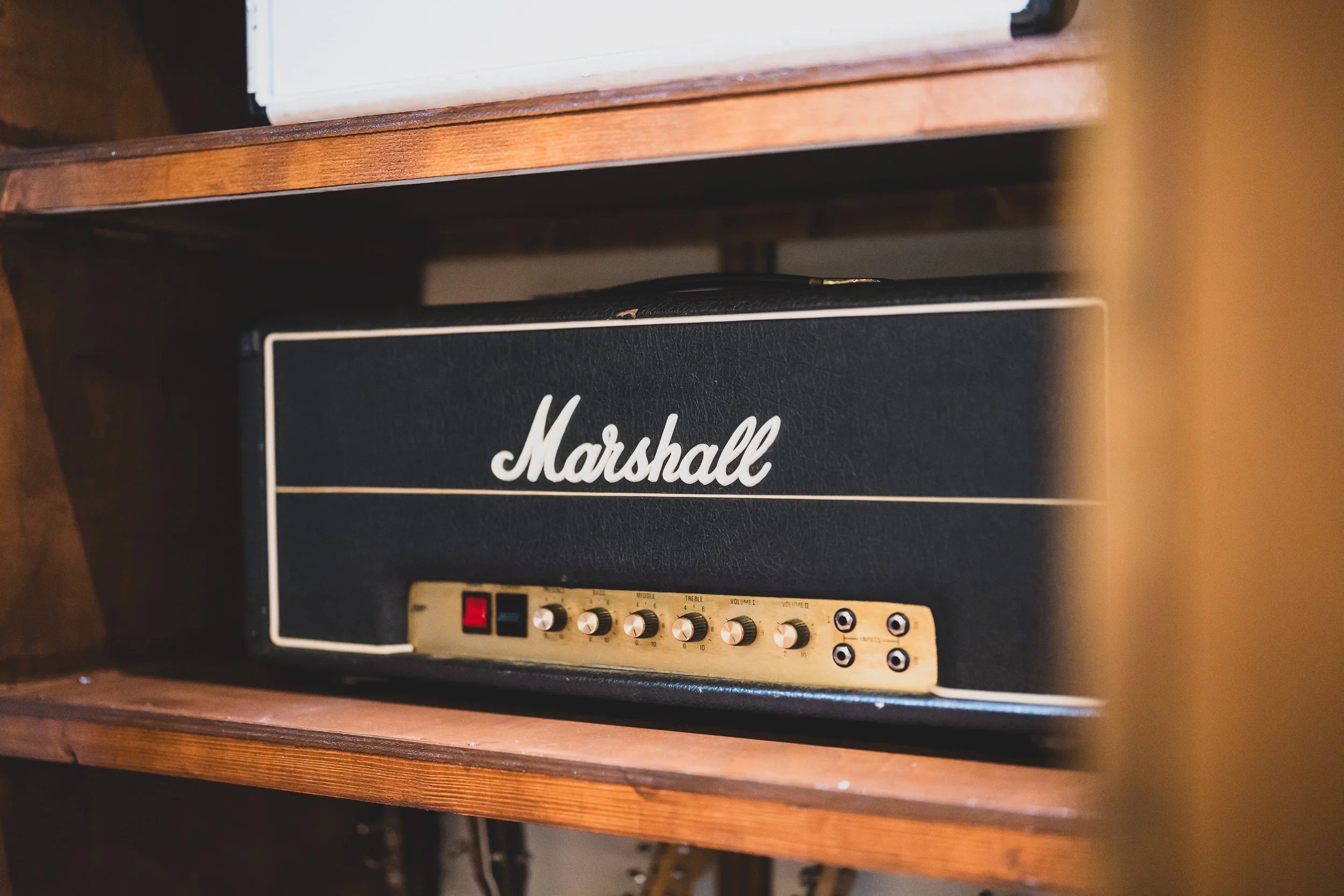 A Marshall guitar amplifier head on a wooden shelf