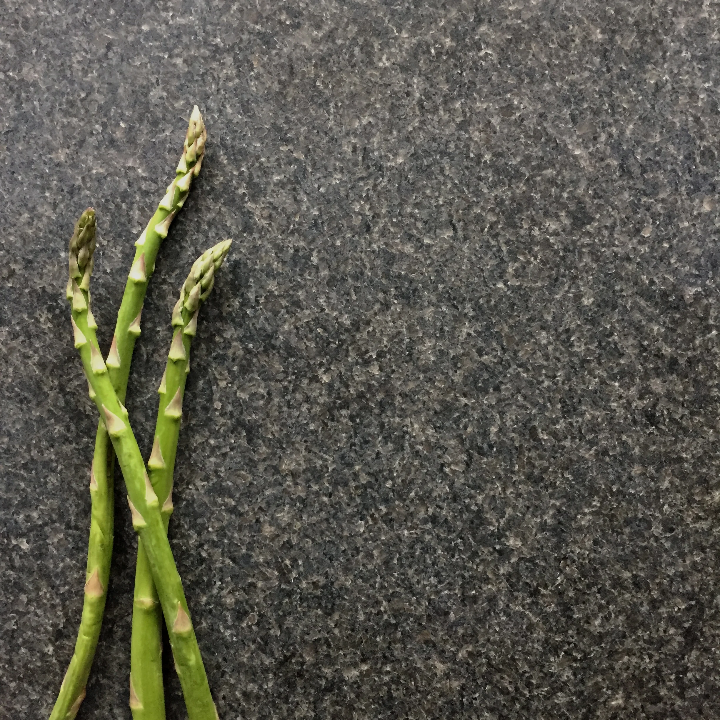 Granitskiva med grön sparris som visar stenens yta och struktur