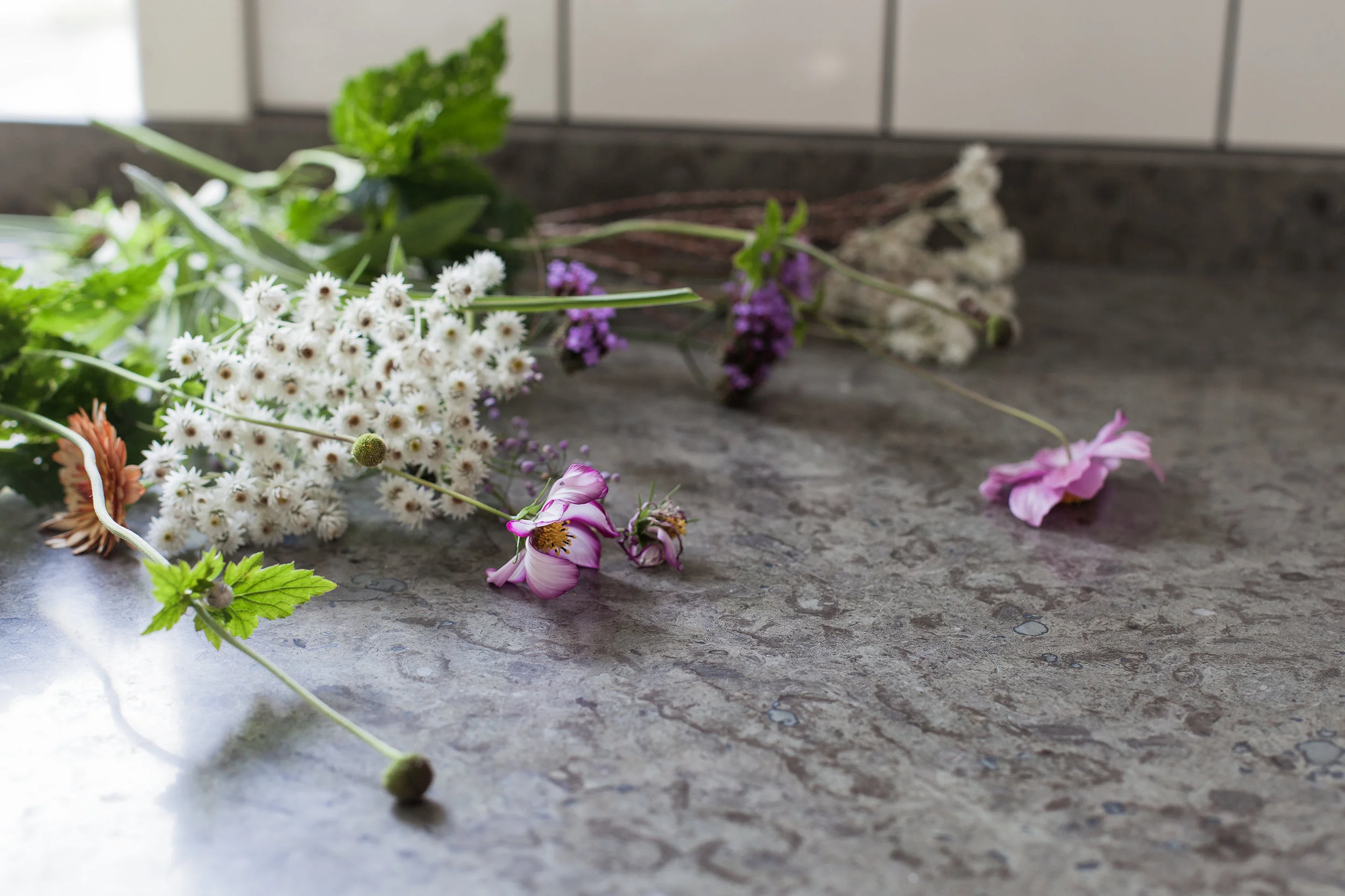 Blommor på grå stenskiva som visar yta och struktur på bänkskiva i sten