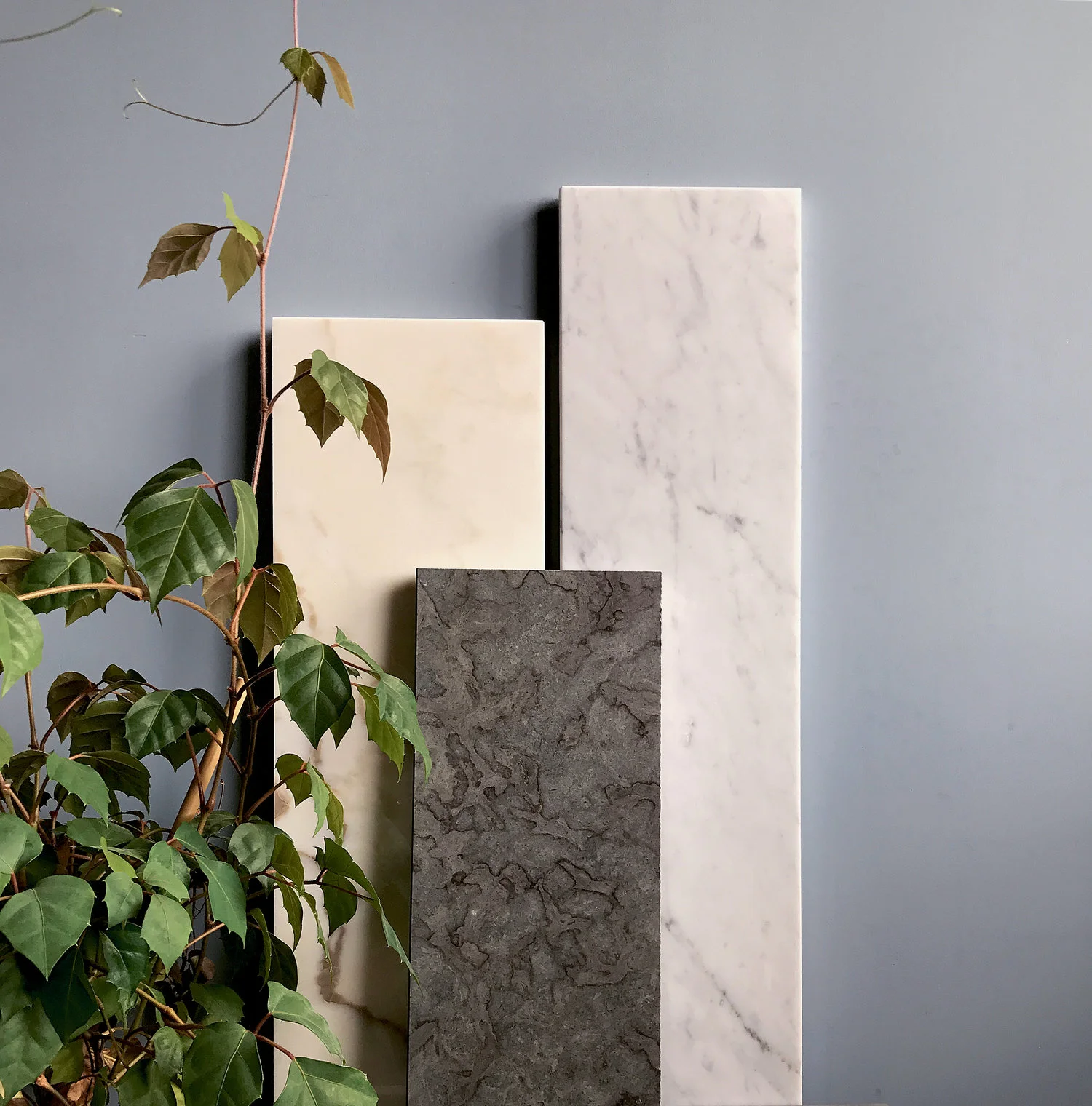 Fönstervänkar i natursten lutade mot vägg bredvid växt