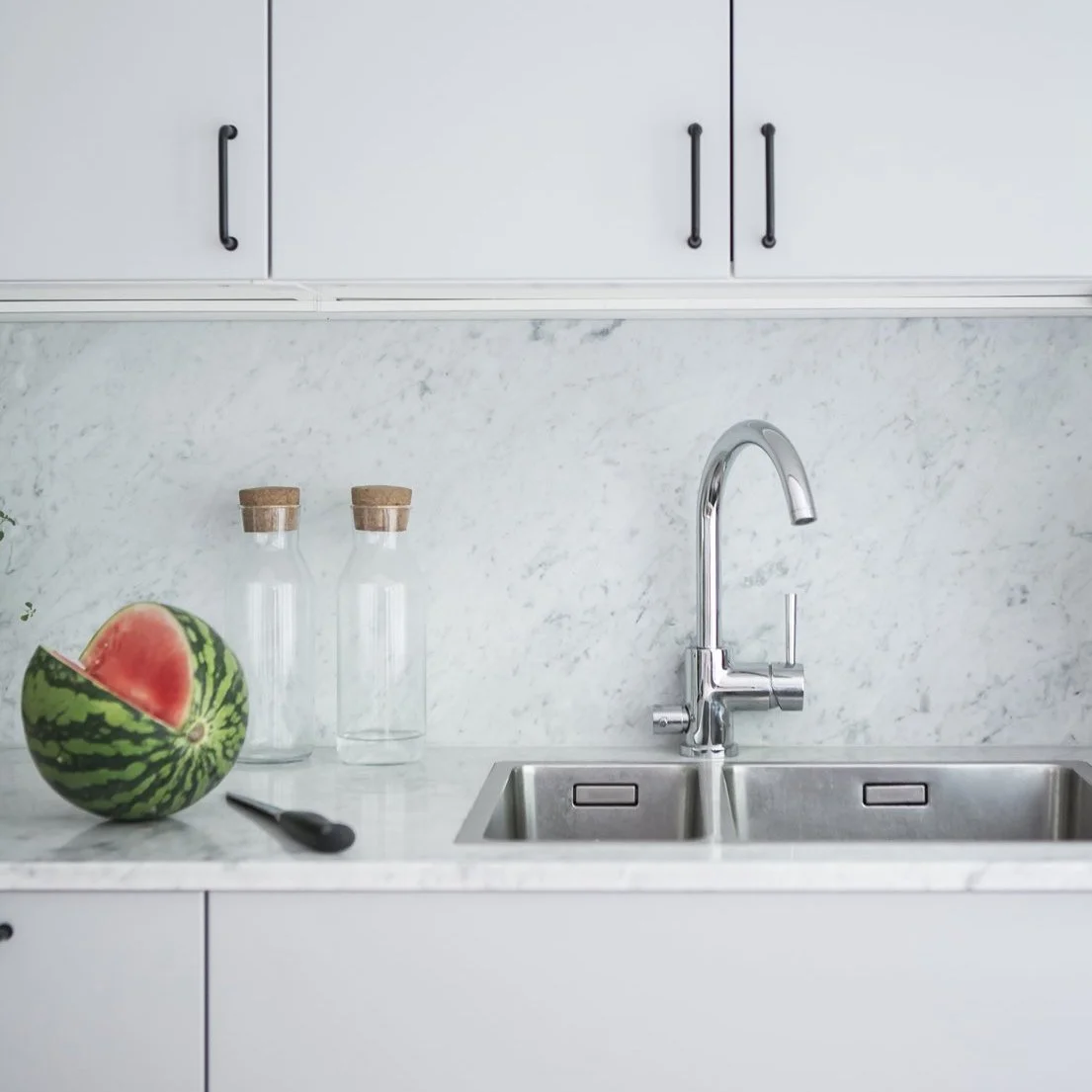 Ljust kök med diskho och bänkskiva i sten