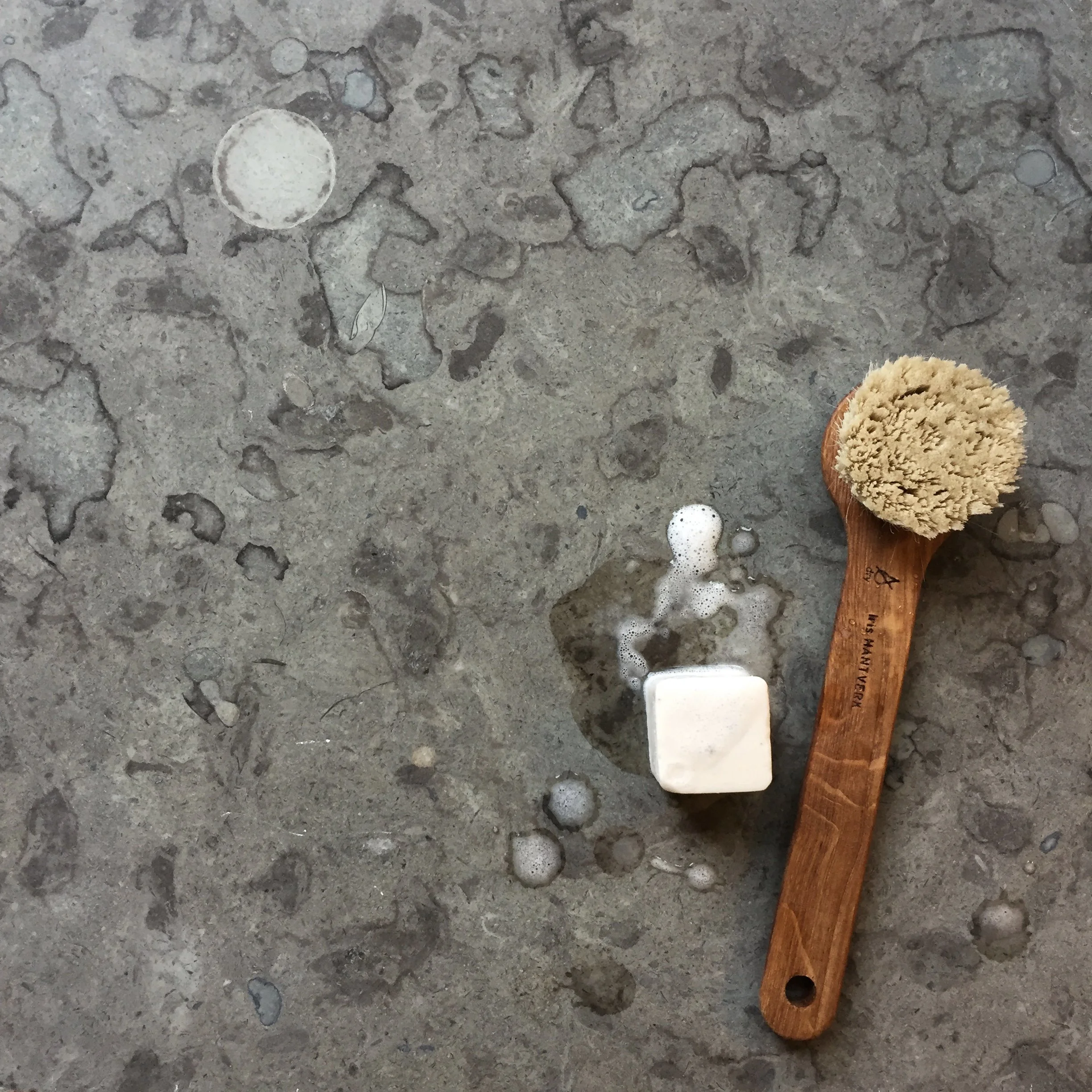 Borste och rengöringsmedel på stenskiva - skötsel av kalksten, marmor och granit