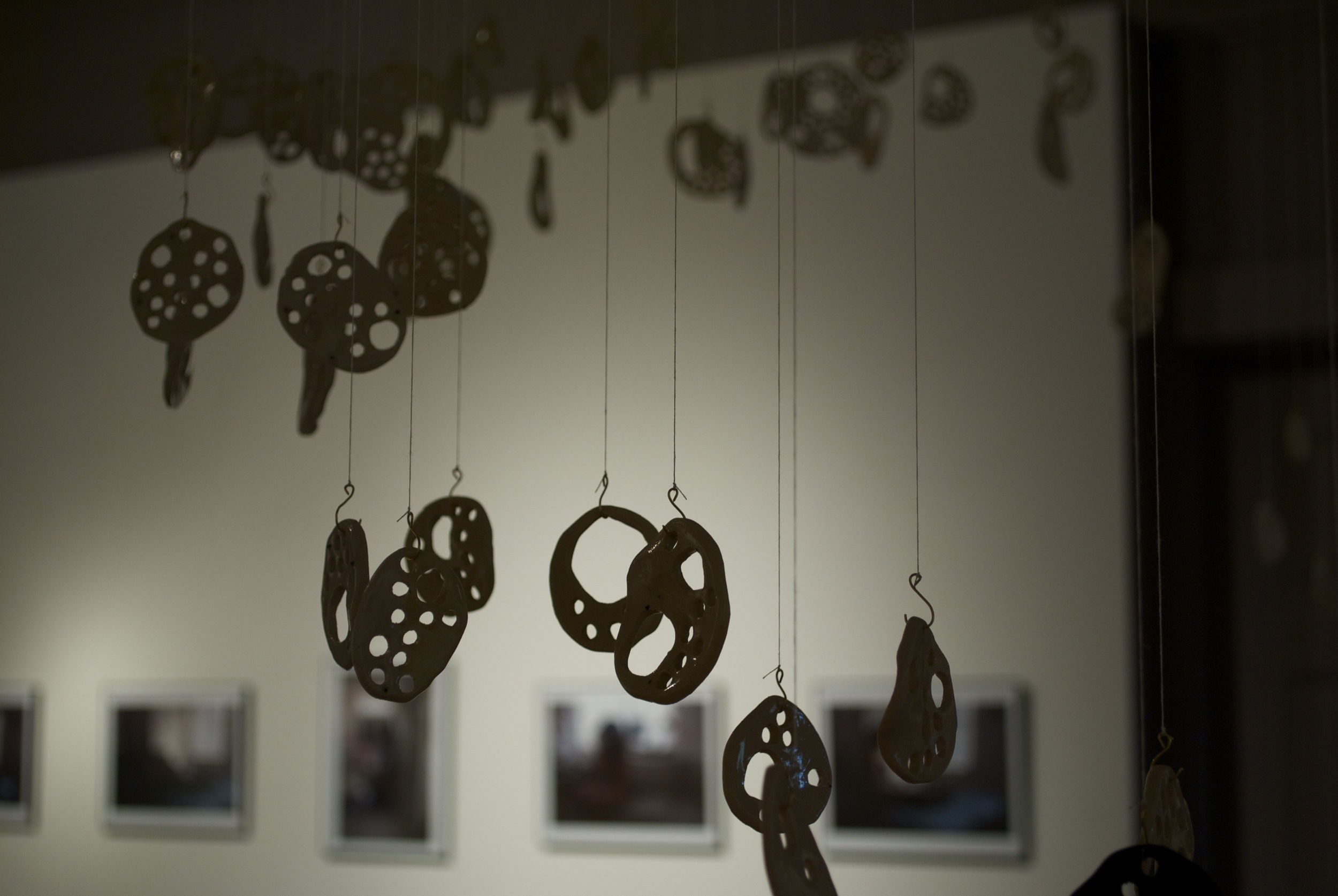 Black ceramic circles with organic holes hanging from strings in Boston MA Shannon May Mackenzie photo