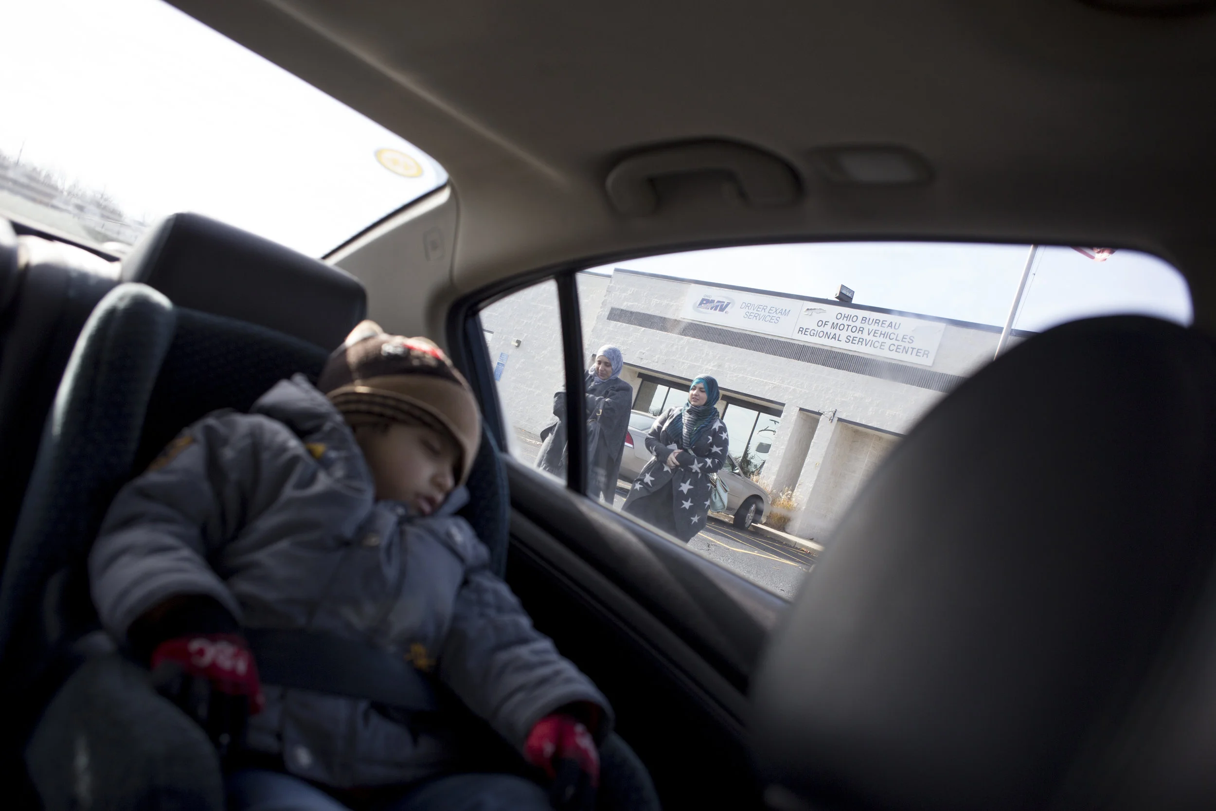 Two year-old Mohamad sleeps in the car as his mother Mariam and Runah, a volunteer for Salaam Cleveland, leave the Bureau of Motor Vehicles after Mariam received news that she failed her drivers permit exam on Wednesday, Dec. 7, 2016. 