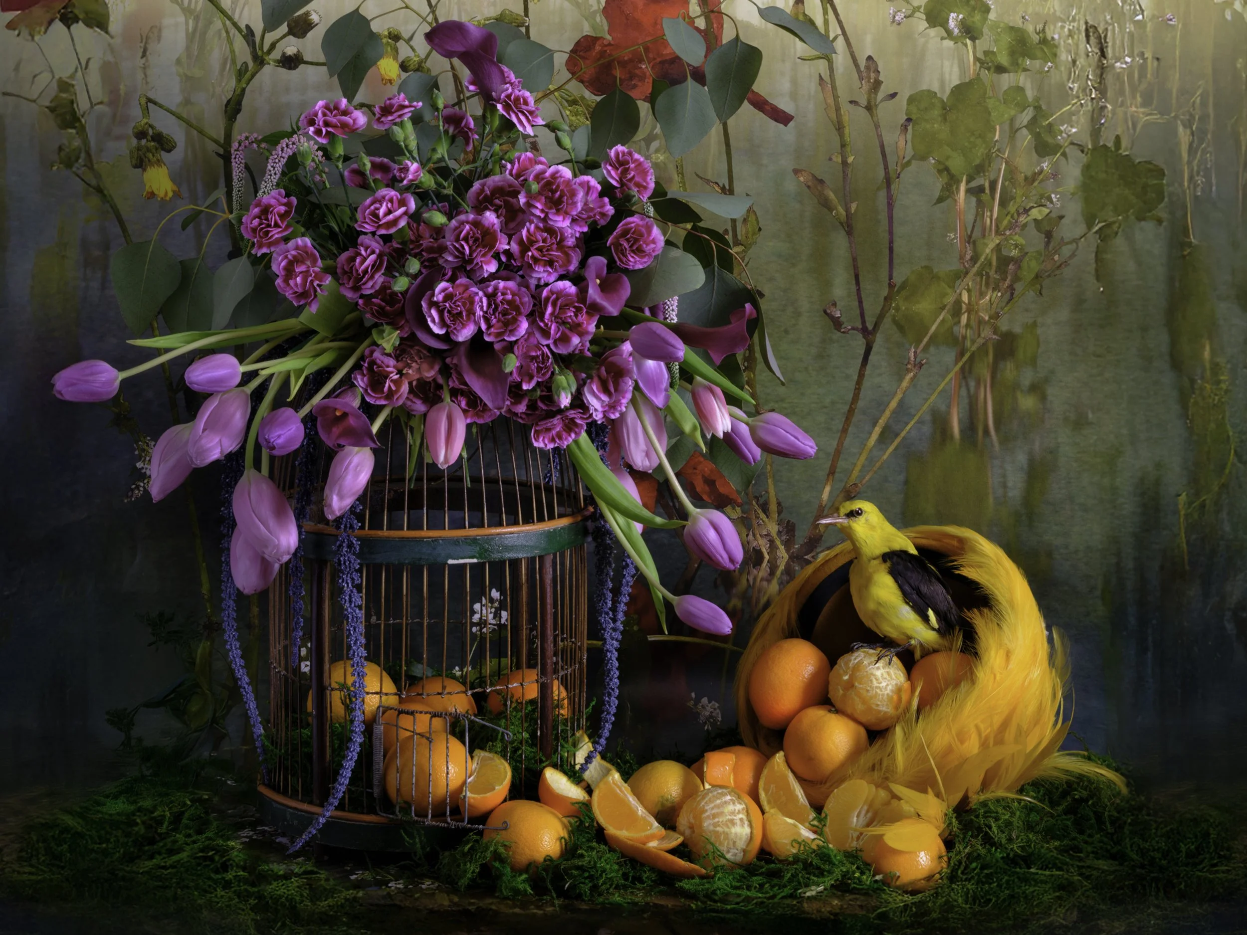 Arrangement of pink and purple flowers, including tulips, carnations, and other blossoms, with green leaves, oranges, clementines, and a yellow bird with black markings in front, set against a natural outdoor background.