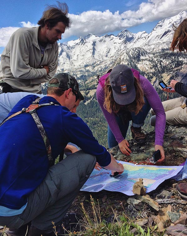Staff members Luke Lamar assisting students Kaleb Juntunen and Sofia Fall with their map reading skills