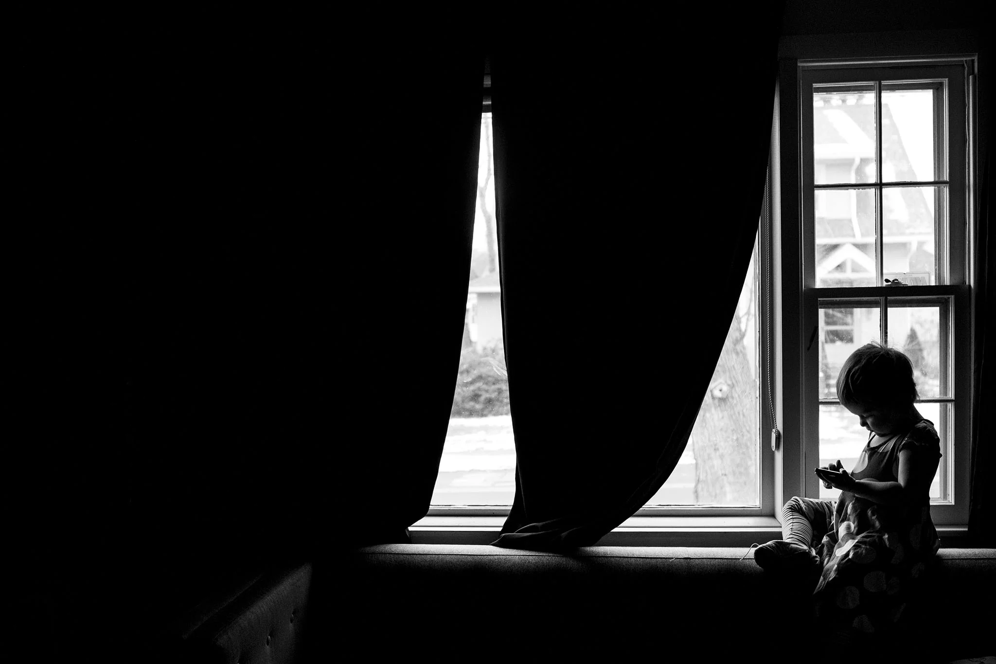 Child sits in window, black and white silhouette portrait by ct photographer chelsea silbereis.