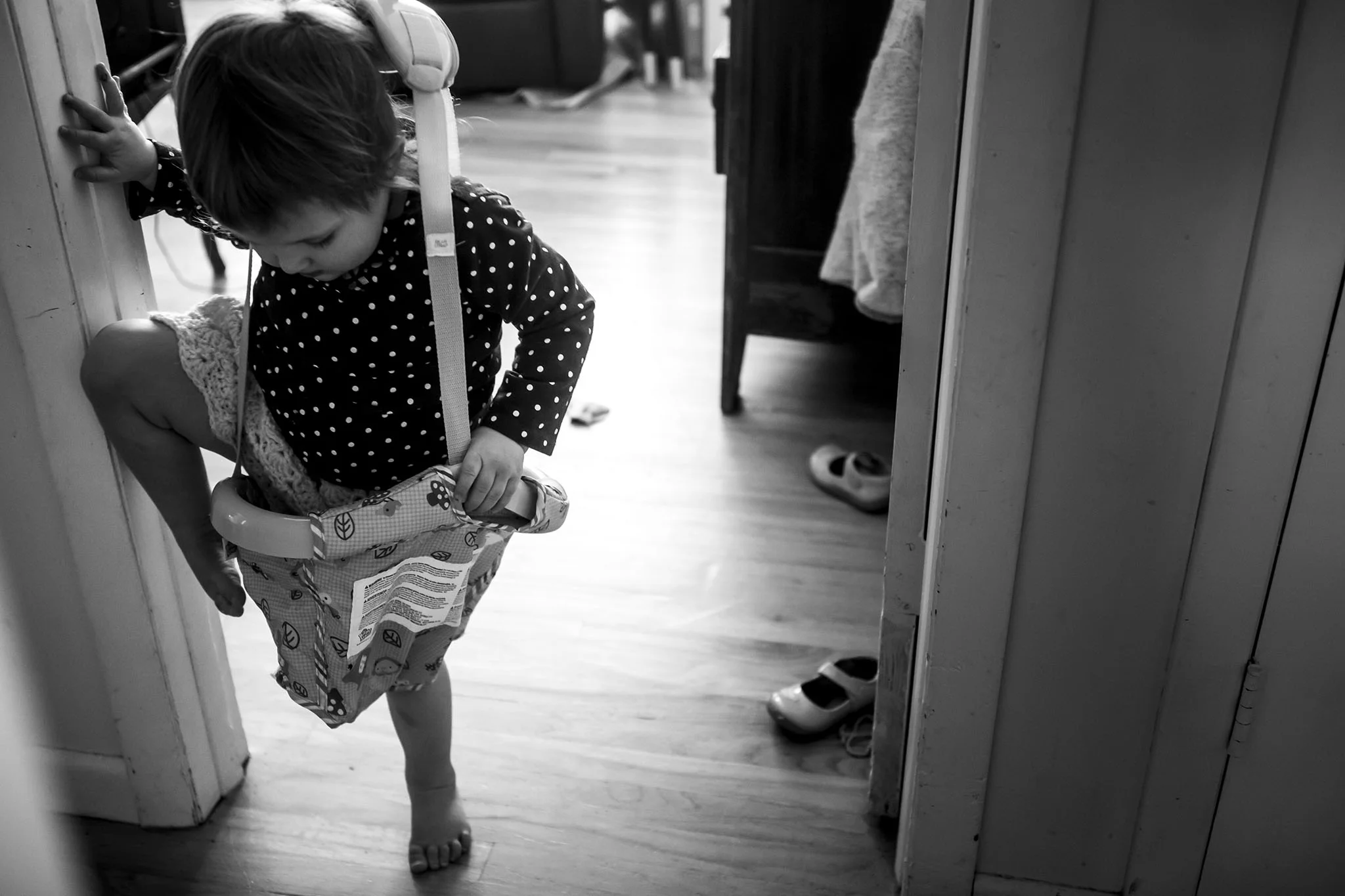 funny family portrait of connecticut toddler trying to get into a baby swing in black and white.
