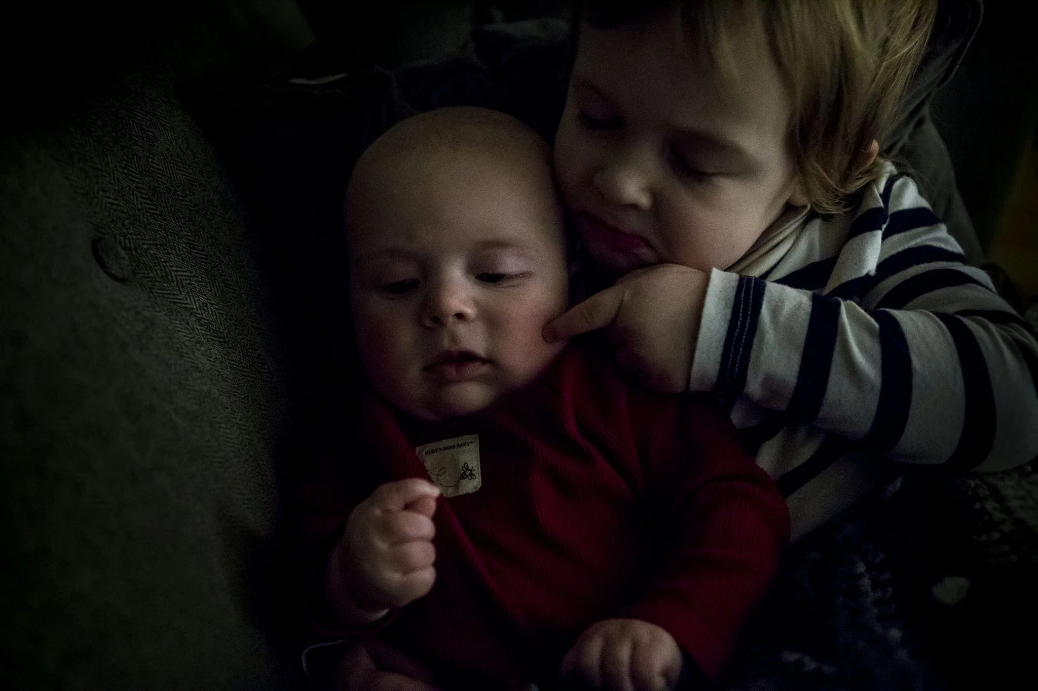 sibling photography in connecticut of big sister holding little brother and poking his cheek.