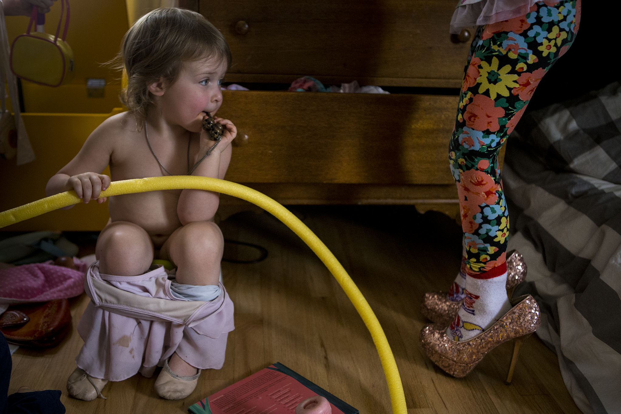 Funny family photo in Connecticut of one girl potty training and another girl wearing mama's sequined high healed shoes.