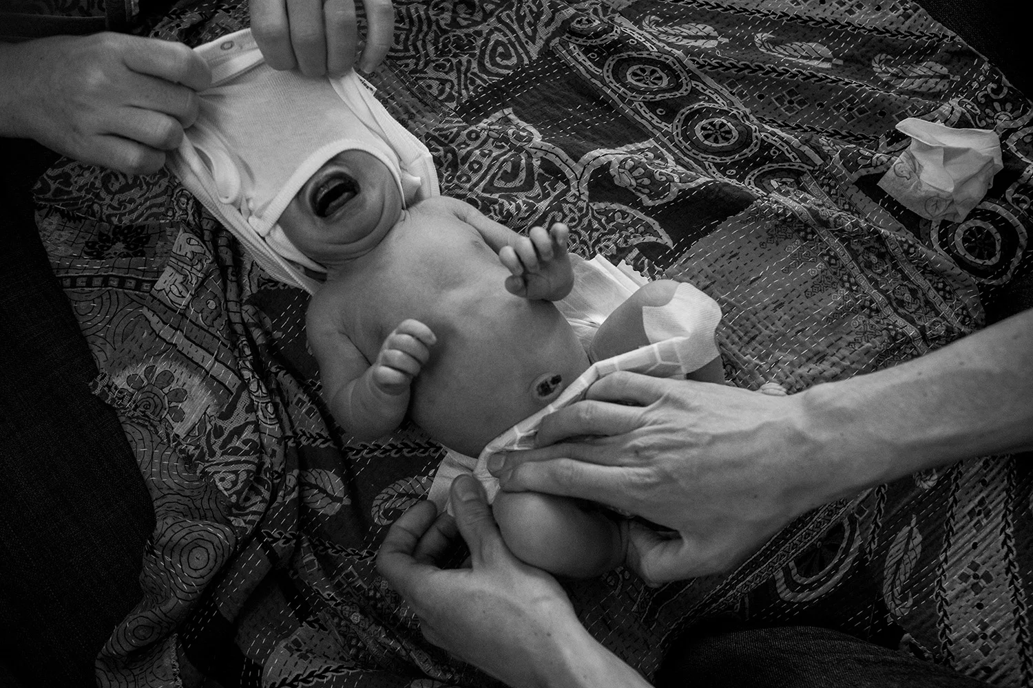 Parents hands tend to crying Boston newborn.