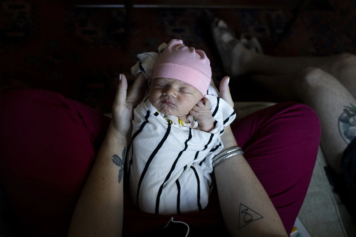 Real life portrait of Boston newborn swaddle and snuggled into mom’s arms.