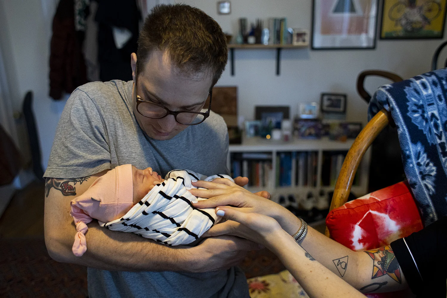Mother’s tender hands passes newborn baby to father.