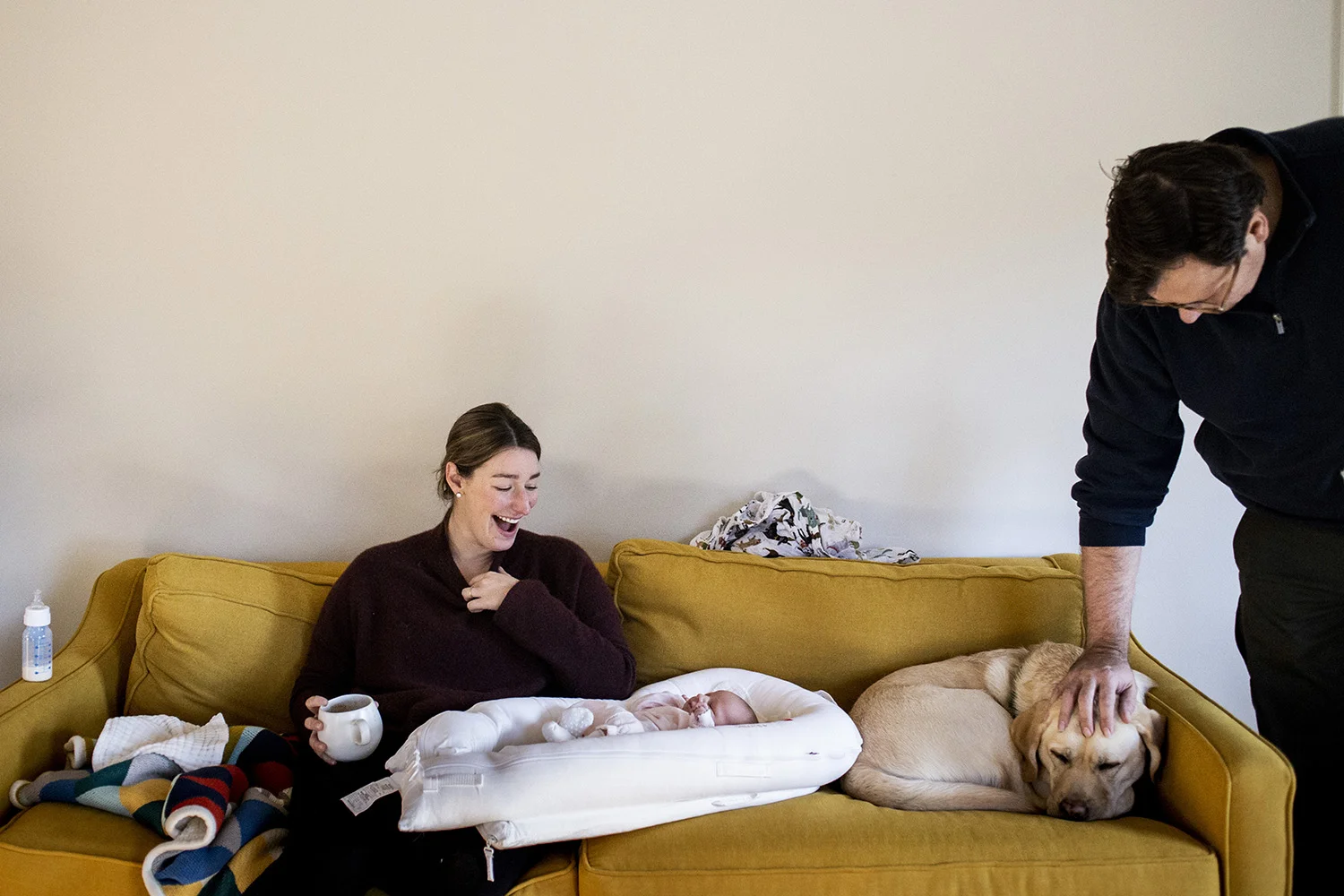 Boston newborn life on the couch with mom, dad, baby and yellow lab.