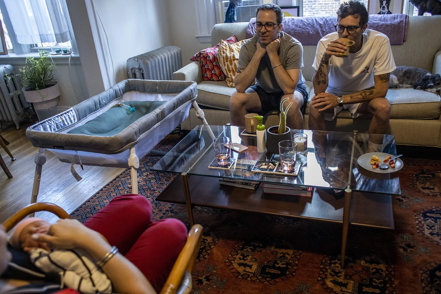 Dad and uncle look on as mother holds newborn baby in Boston’s Fenway neighborhood.