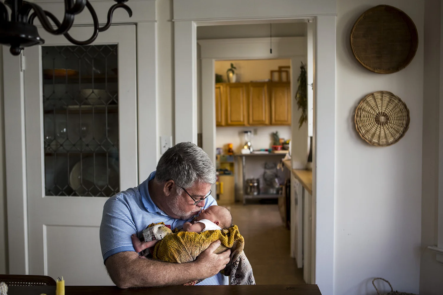 Boston Grandpa kisses newborn granddaughter.