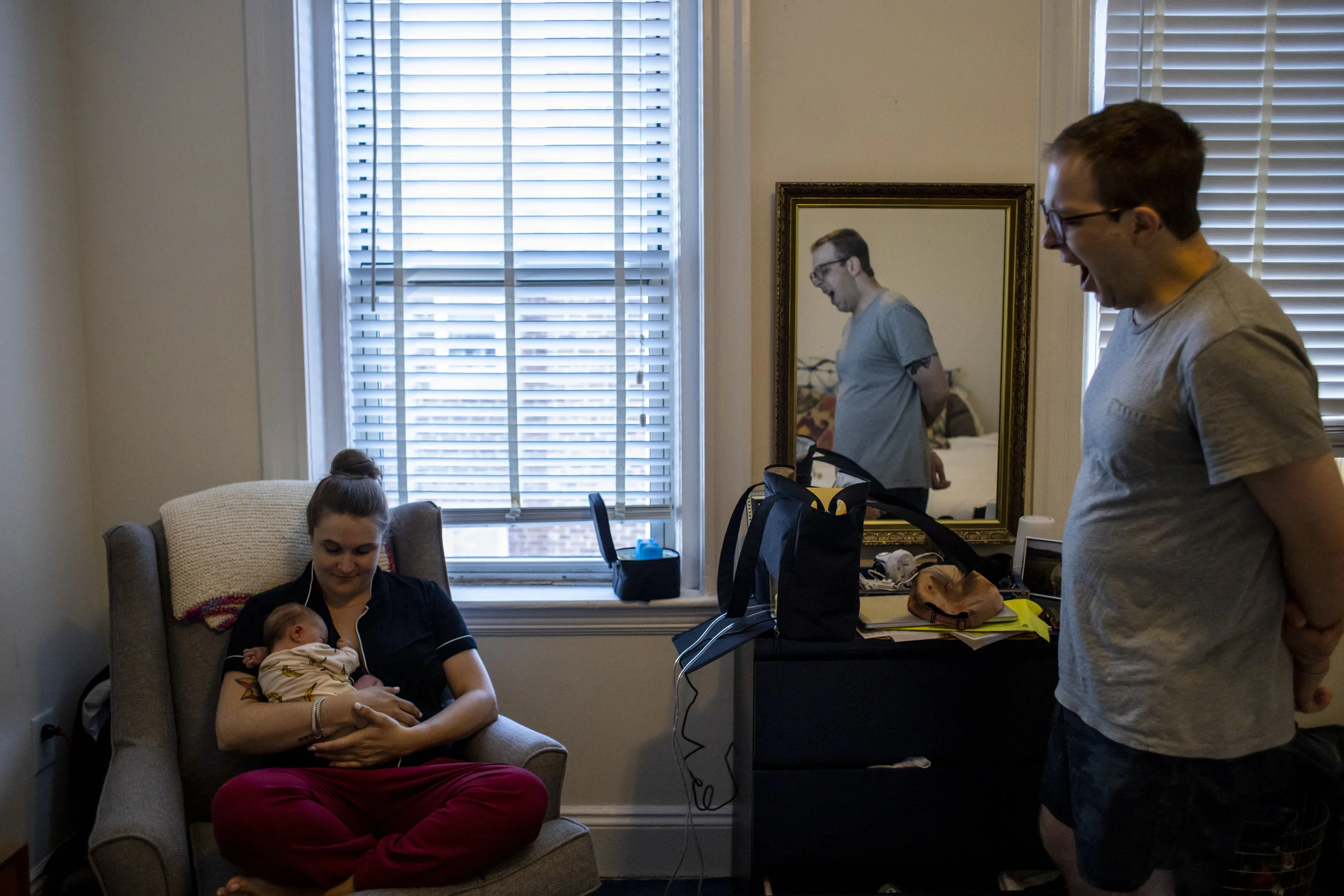 Exhausted dad of newborn baby yawns in unique portrait of Boston Family life.