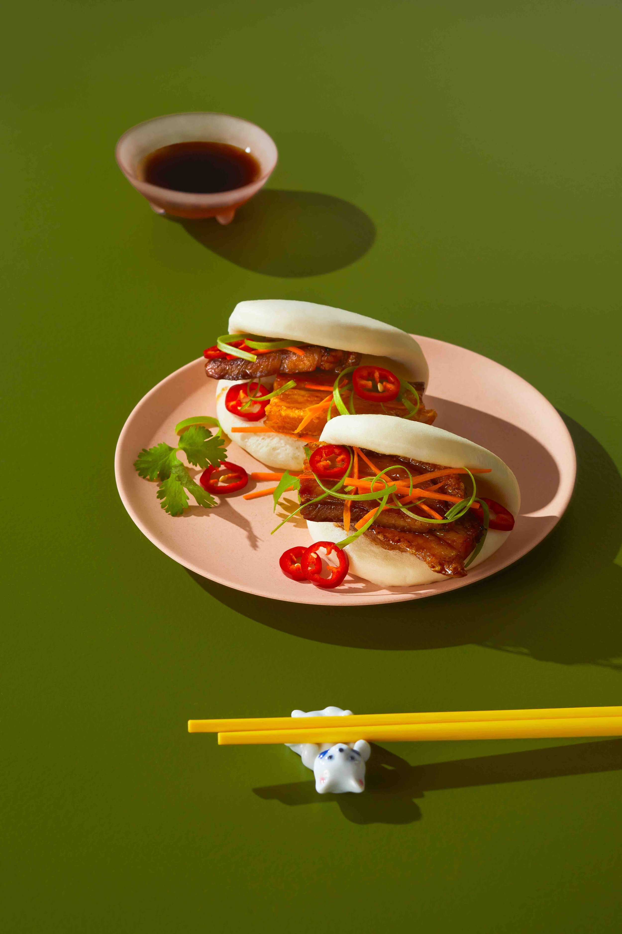 porkbelly buns on pink plate with chopsticks, kitty chopsticks holder on green table.jpg