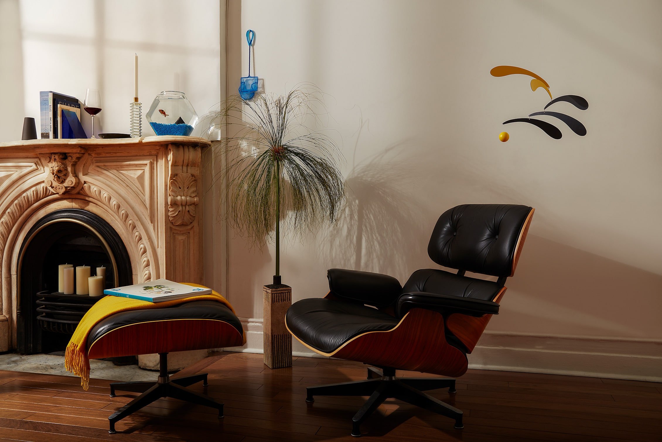 Eames lounge chair in front of a marble fireplace with a goldfish on the mantle.jpg