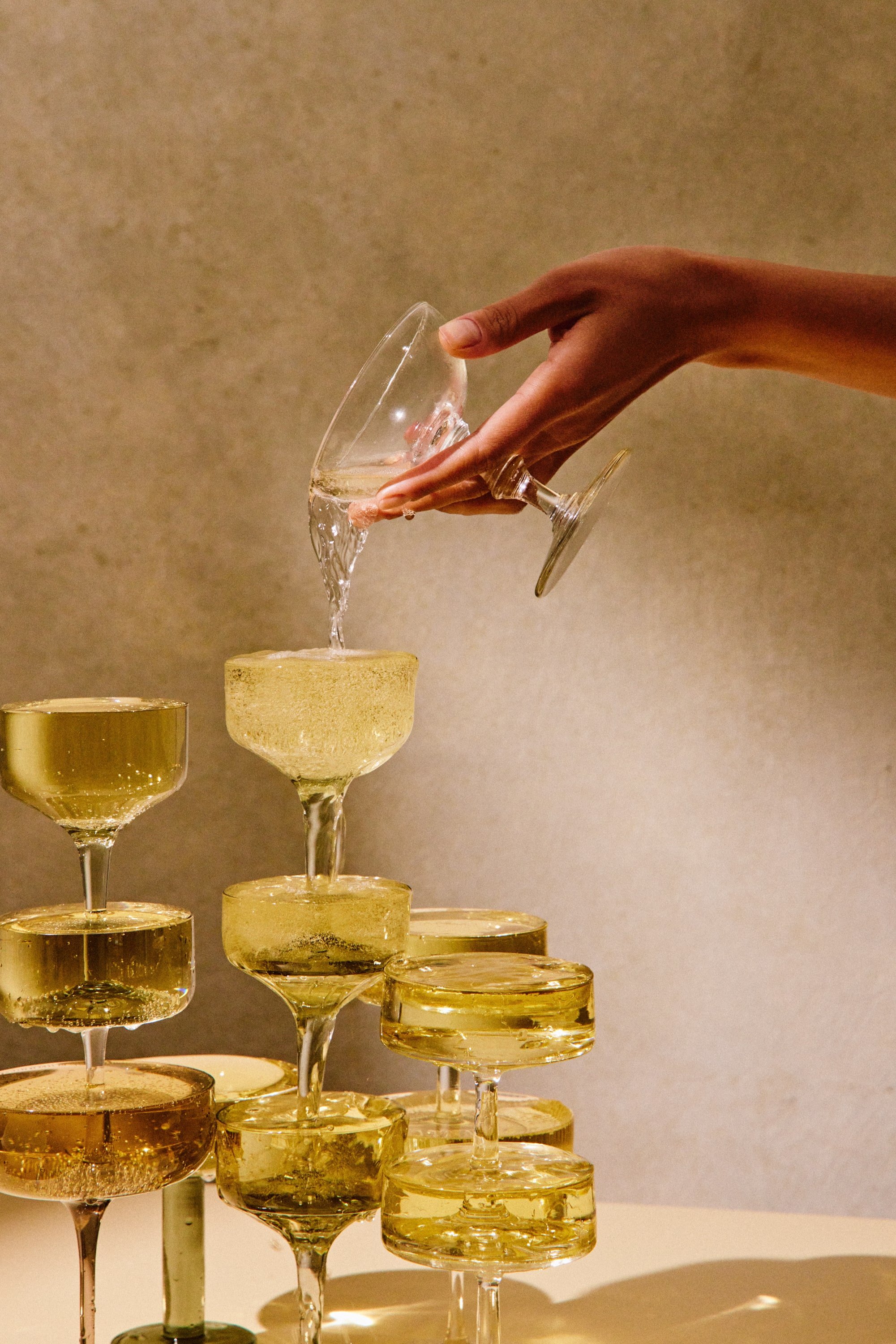 champagne tower with mismatched coupe glasses pouring by hand.jpg