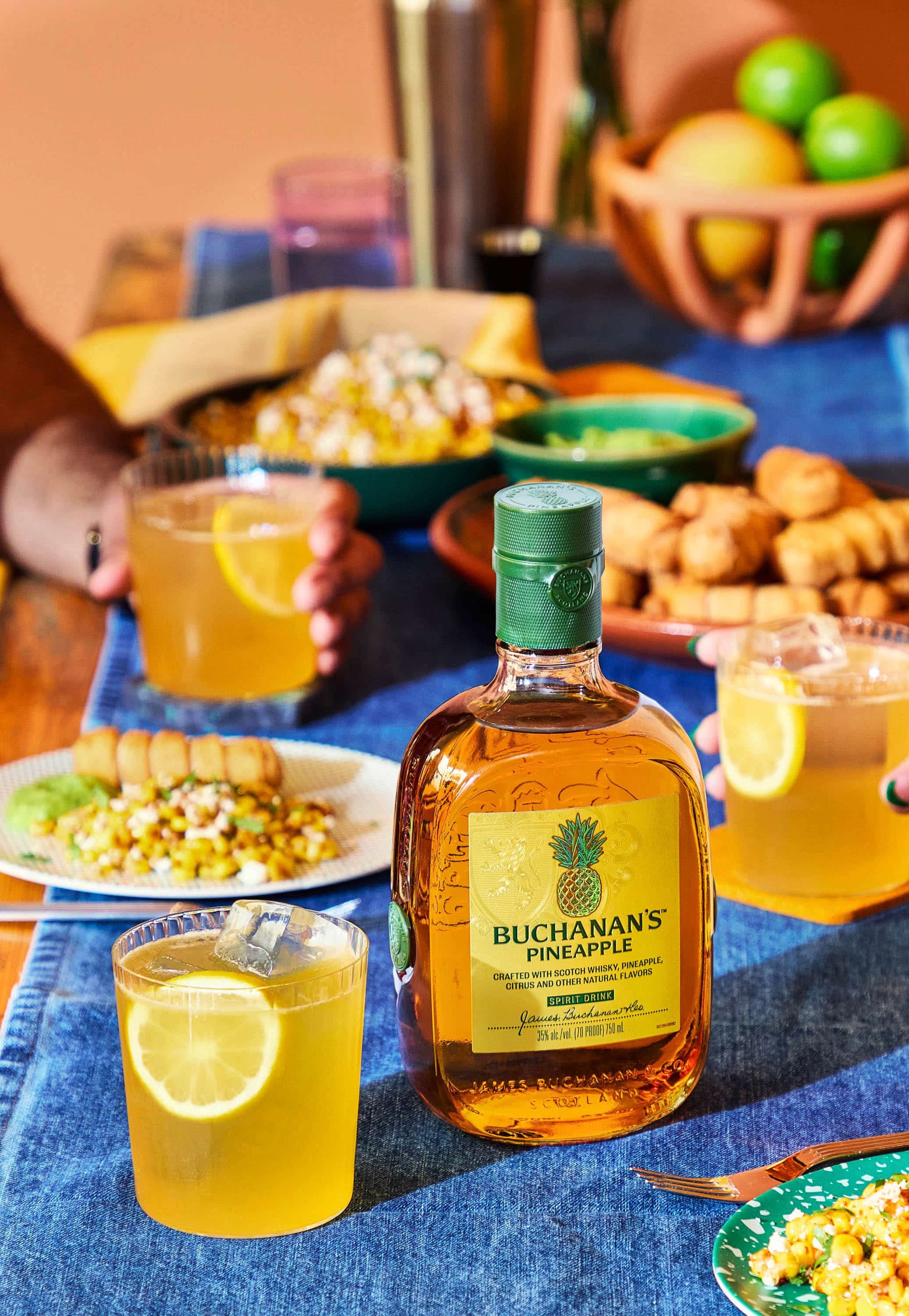 whiskey cocktail on a denim runner with snacks and terracotta fruit bowl background.jpg