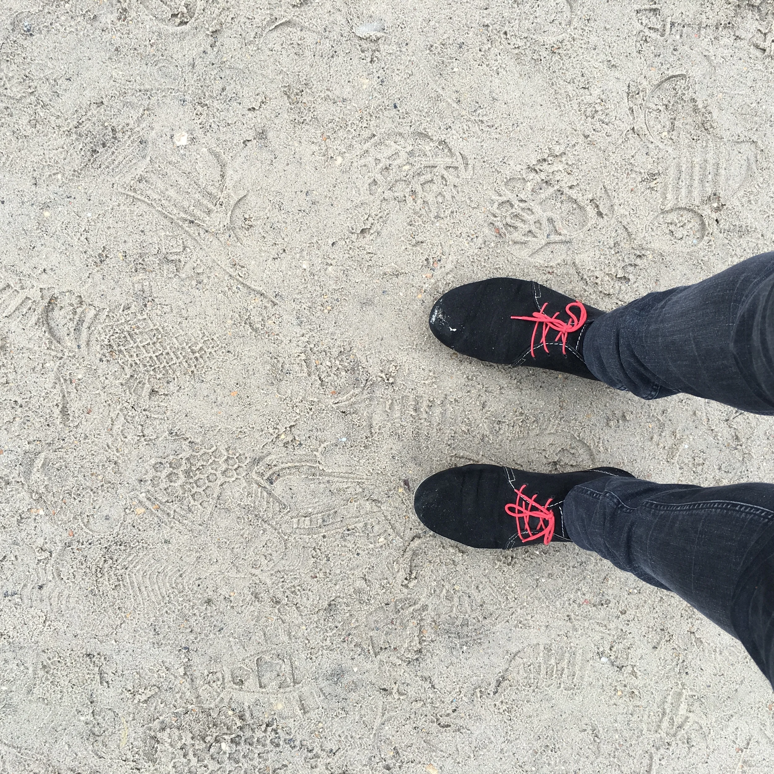 Black suede shoes on wet sand