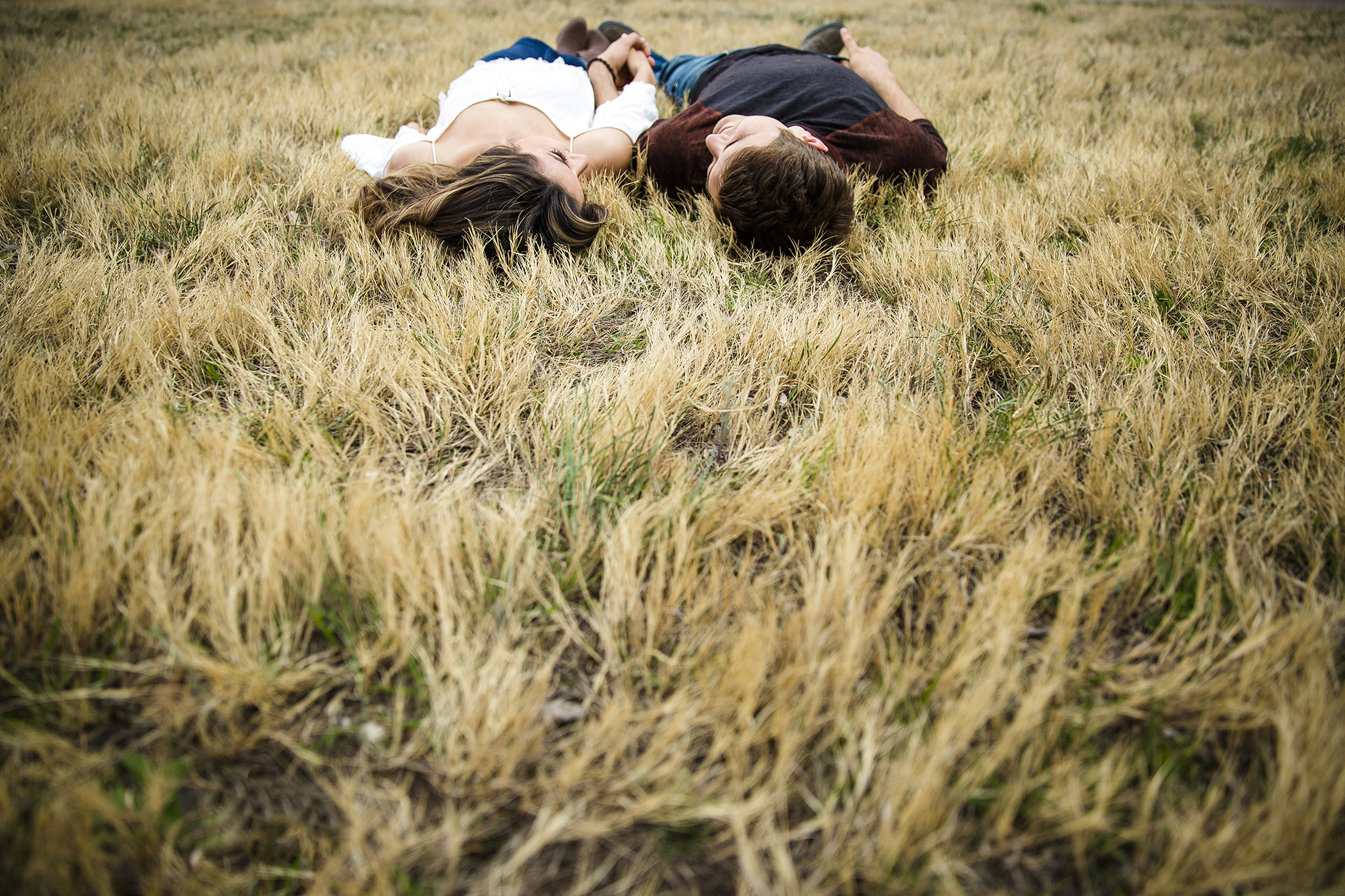 laying in the grass, romantic, holding hands, creative engagement photography