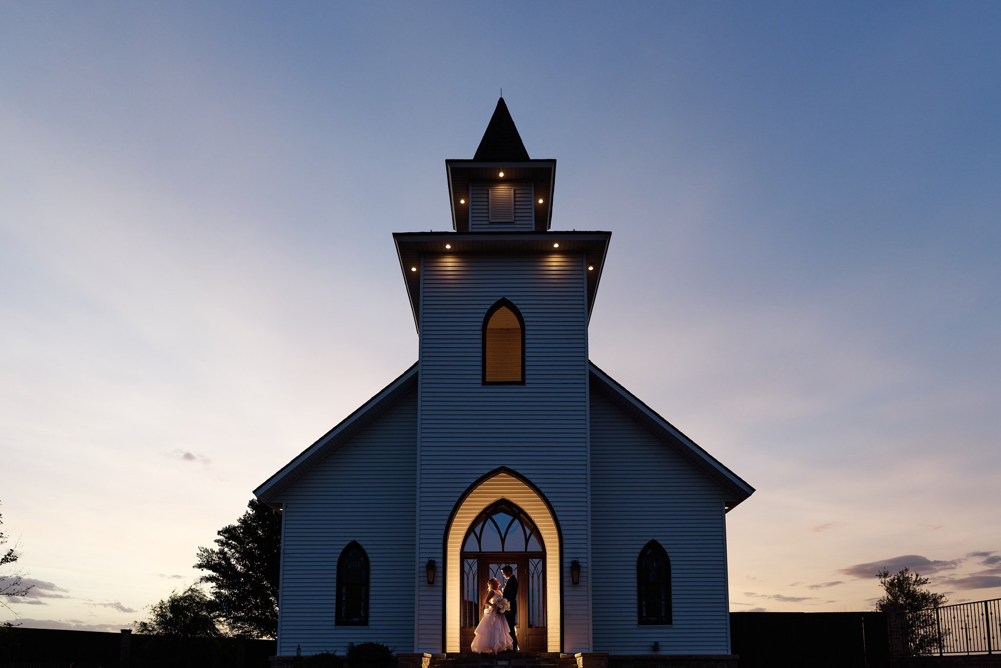 Couple poses in front of chapel at sunset