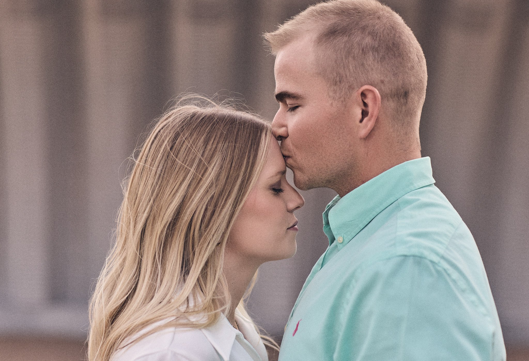 groom kisses fiance on forehead during engagement session