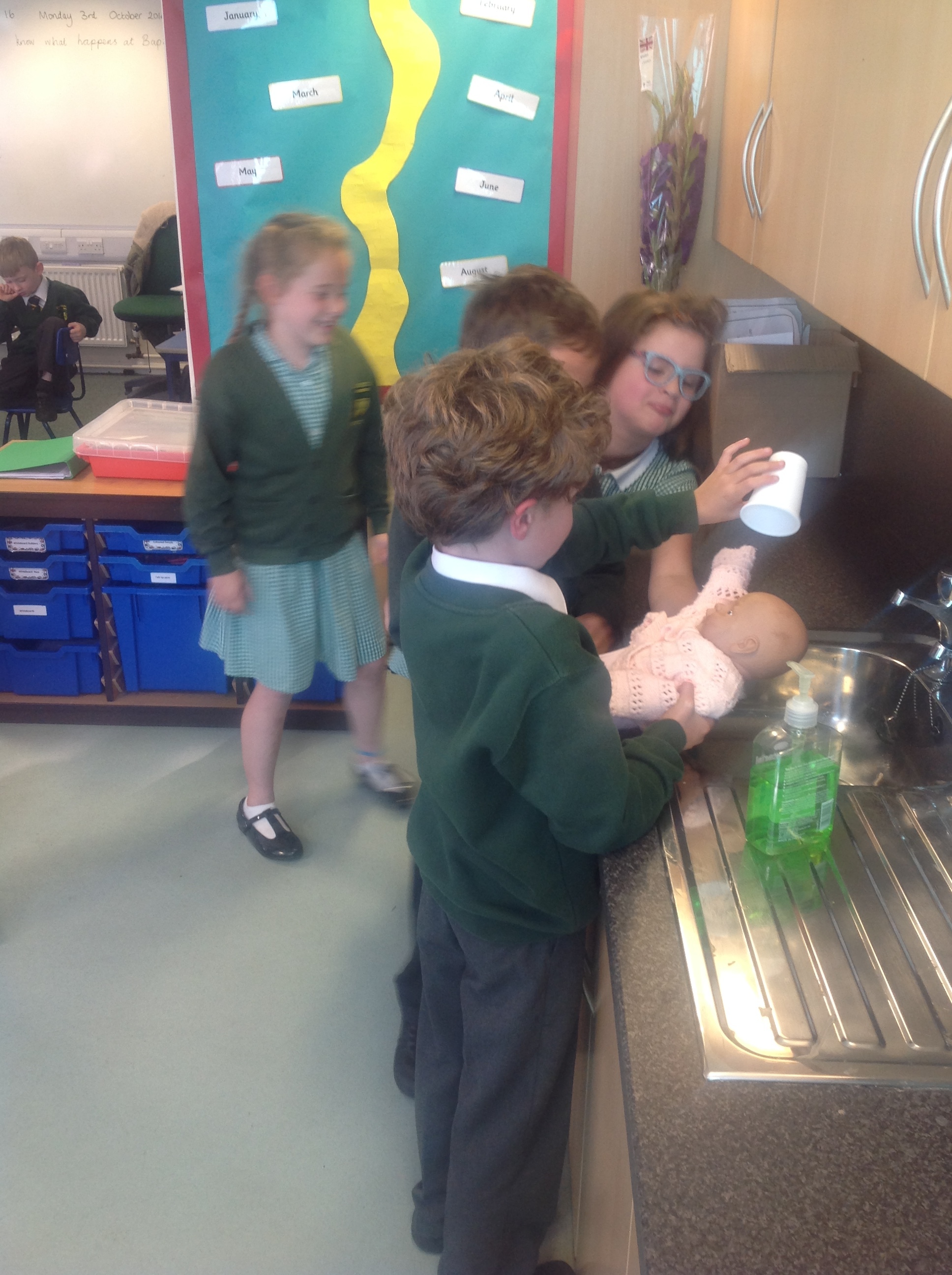 The baby is baptised with holy water as it is poured over their head three times, at the baptismal font (Year 3 sink!)