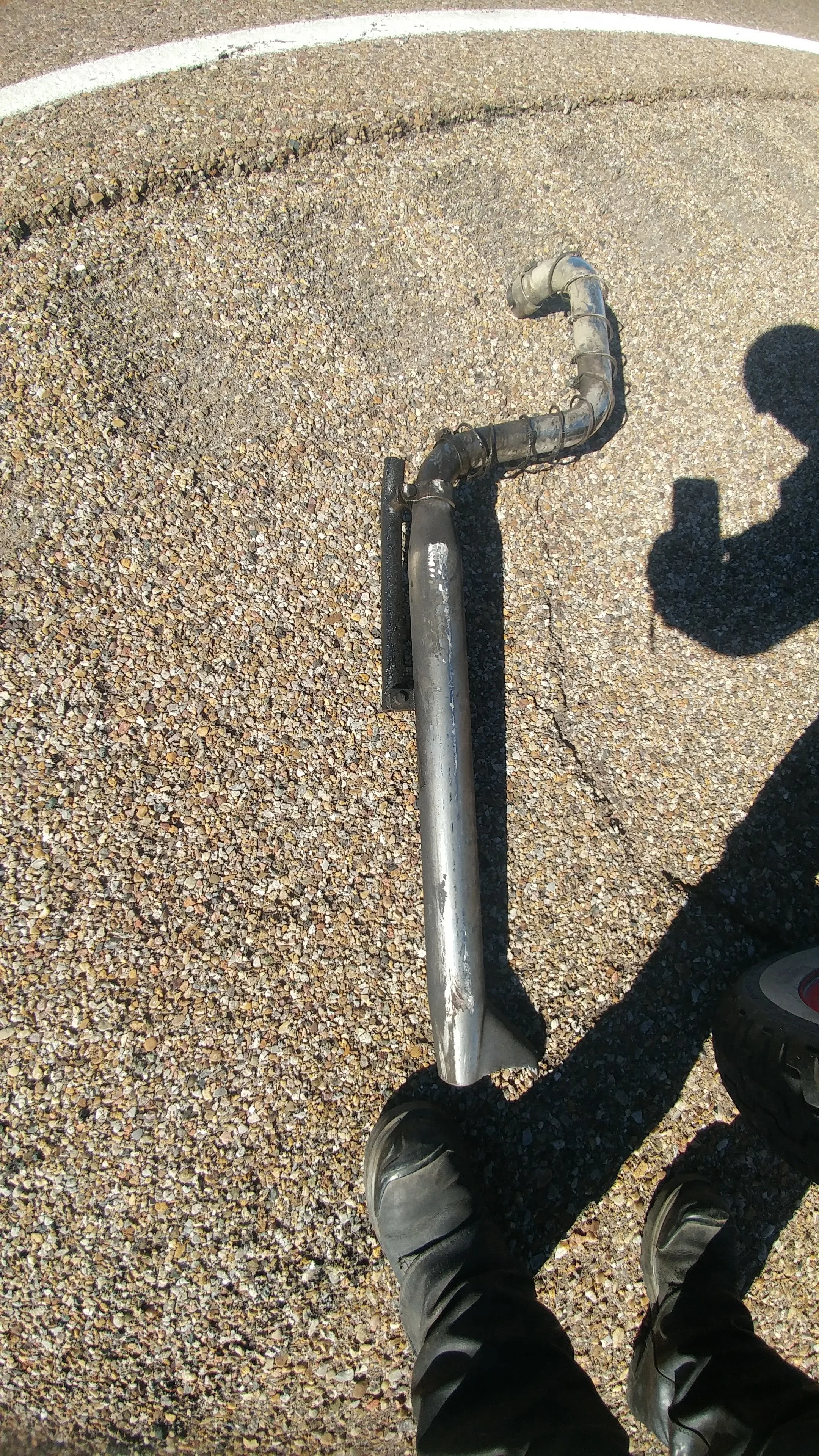 Exhaust pipe wrapped in barbed wire laying on highway with broken hanger