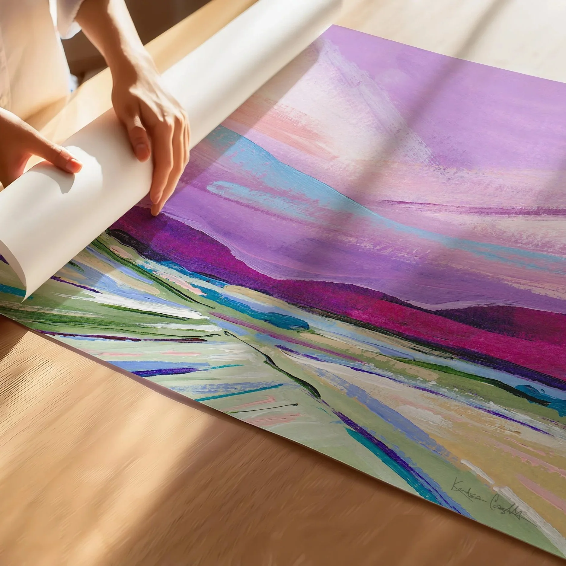 Abstract painting of a landscape with a purple sky, pink and blue clouds, and green and purple hills. The painting is framed in a light wood frame. Art by Kendra Castillo