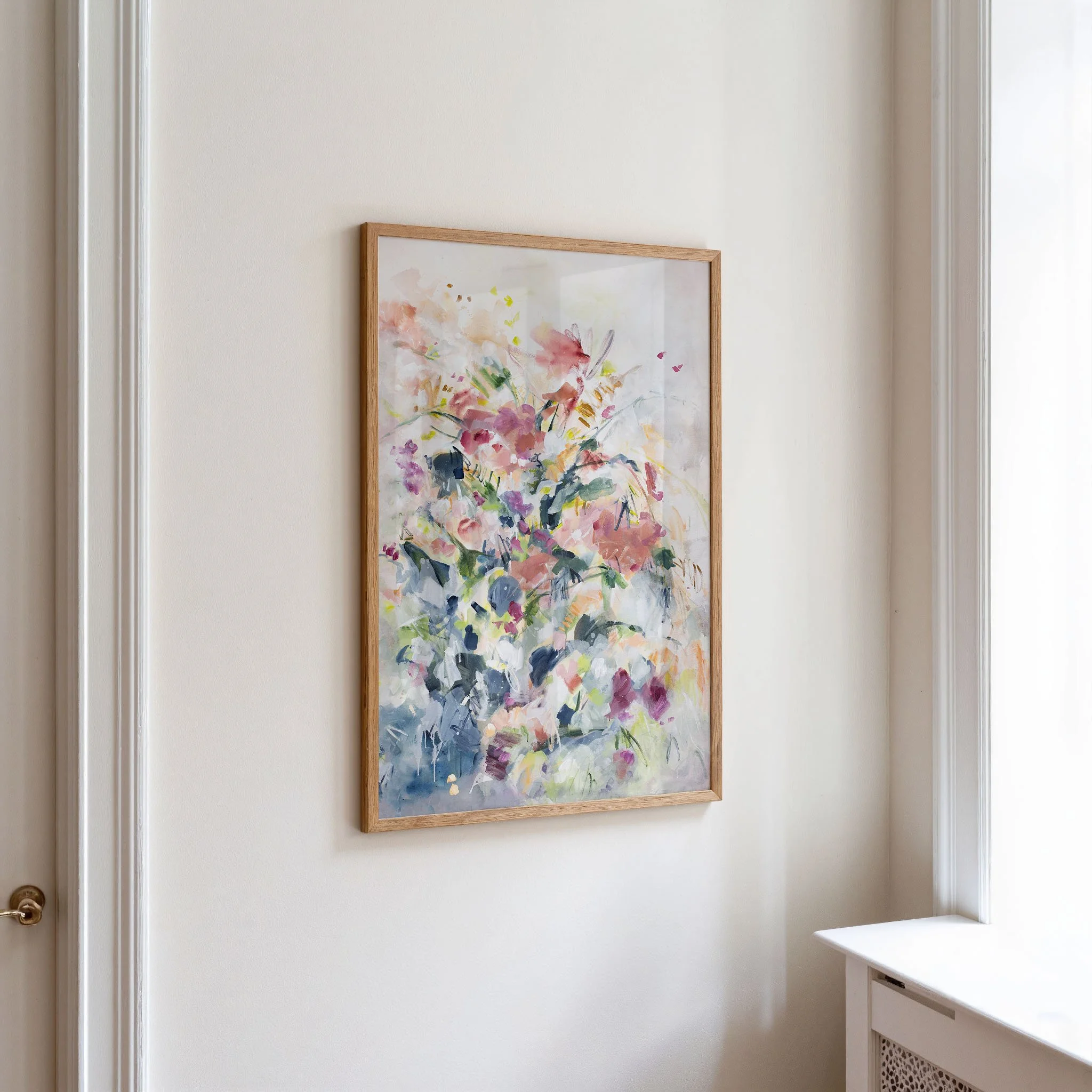 Framed Still Garden vertical floral art print by Kendra Castillo displayed in a modern hallway.